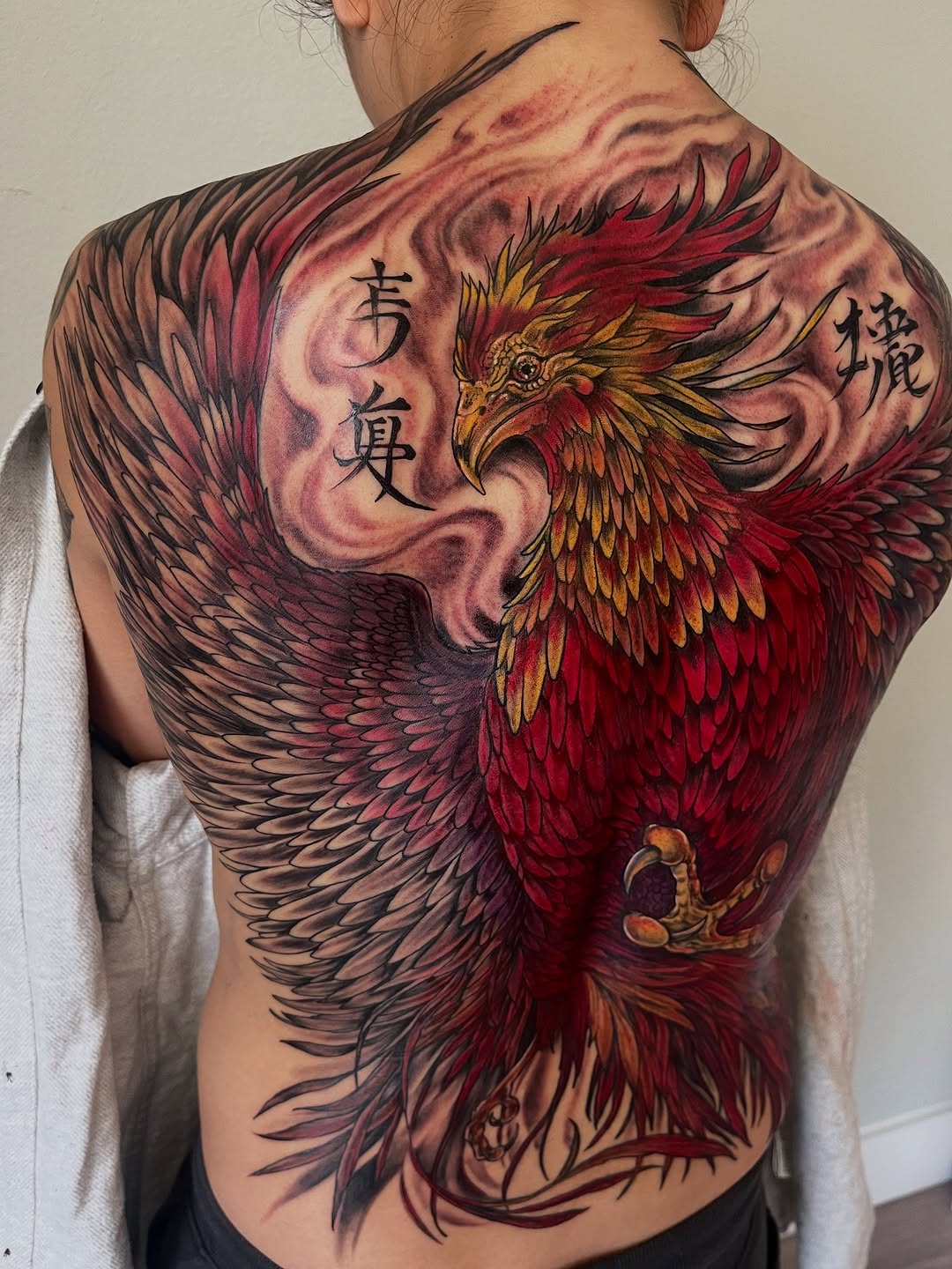 Phoenix with chinese characters realism tattoo on the back by Janelle Cuba