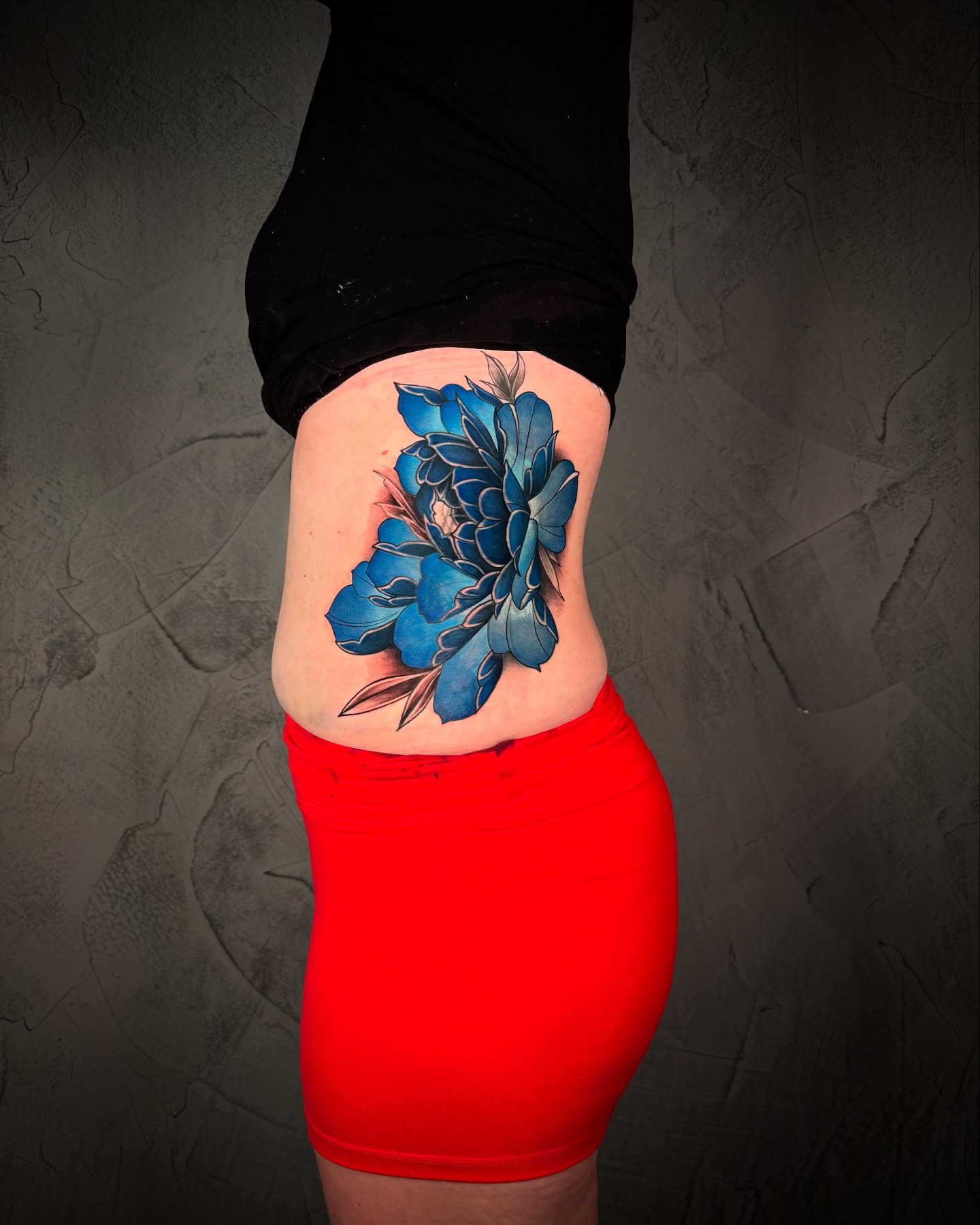 Blue flower dotwork tattoo on the ribs by Ethan Lund