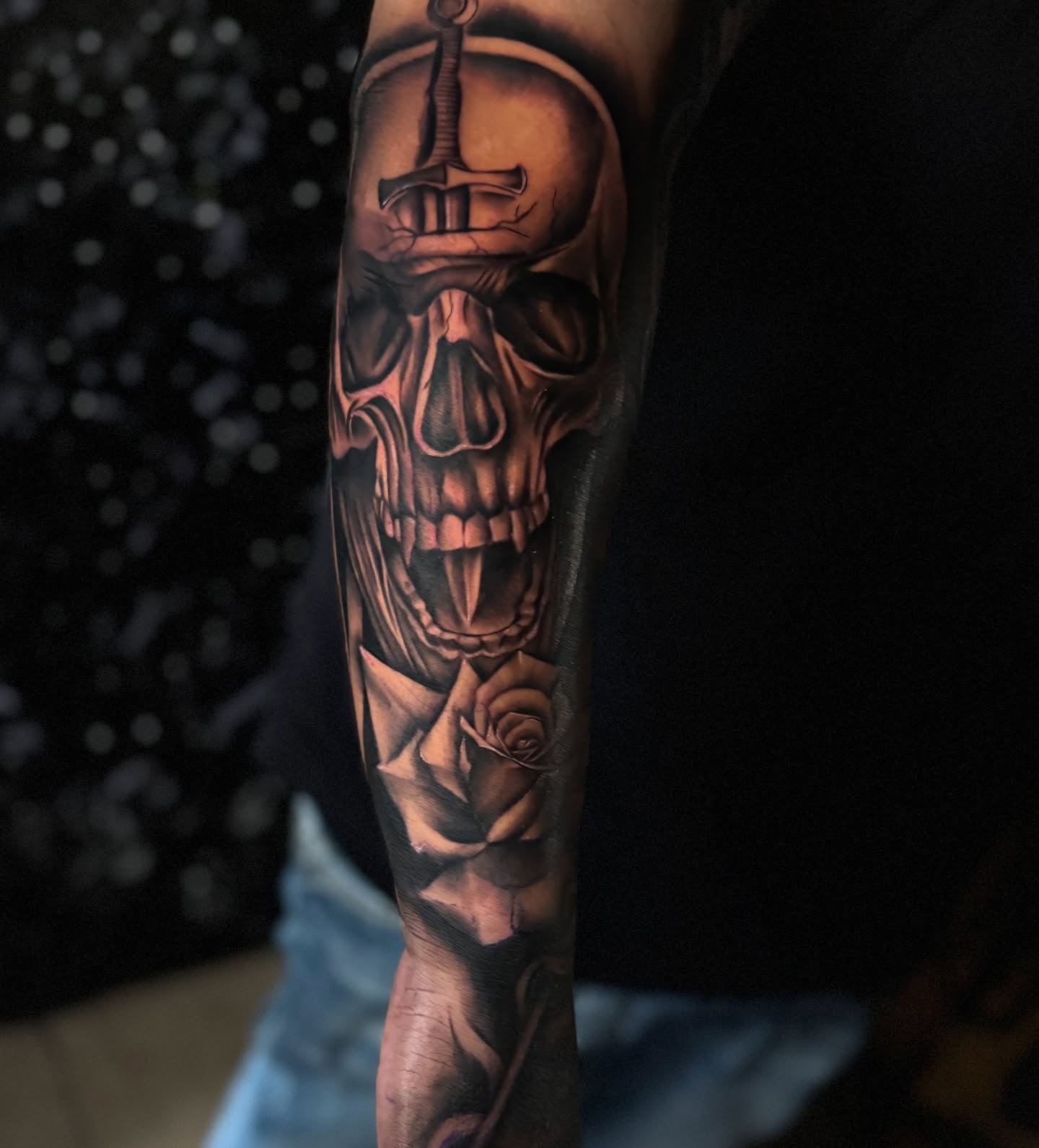 Skull with sword and rose realism tattoo on the forearm by Tattoo Artist