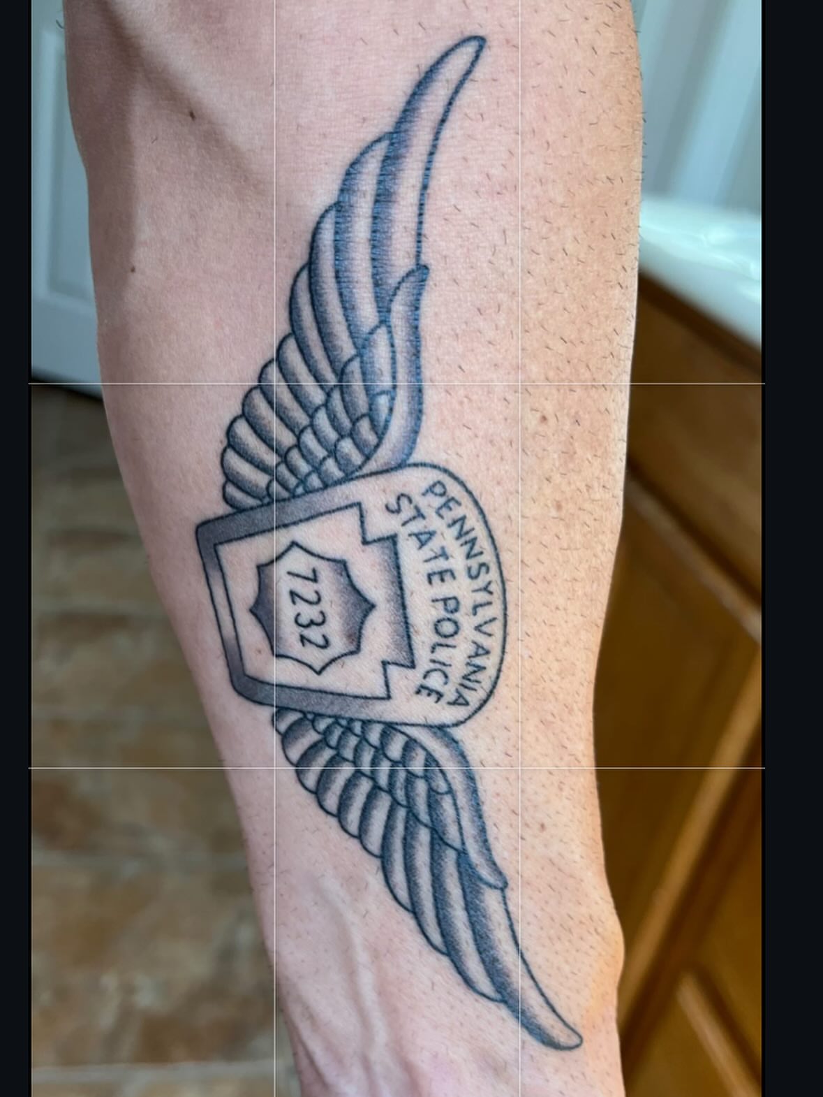 Wings and Pennsylvania State Police badge black and grey tattoo on the forearm by ๐๐๐ฑ๐ฑ๐ฌ๐ฌ ๐๐ฏ๐ฑ๐ฆ๐ฐ๐ฑ