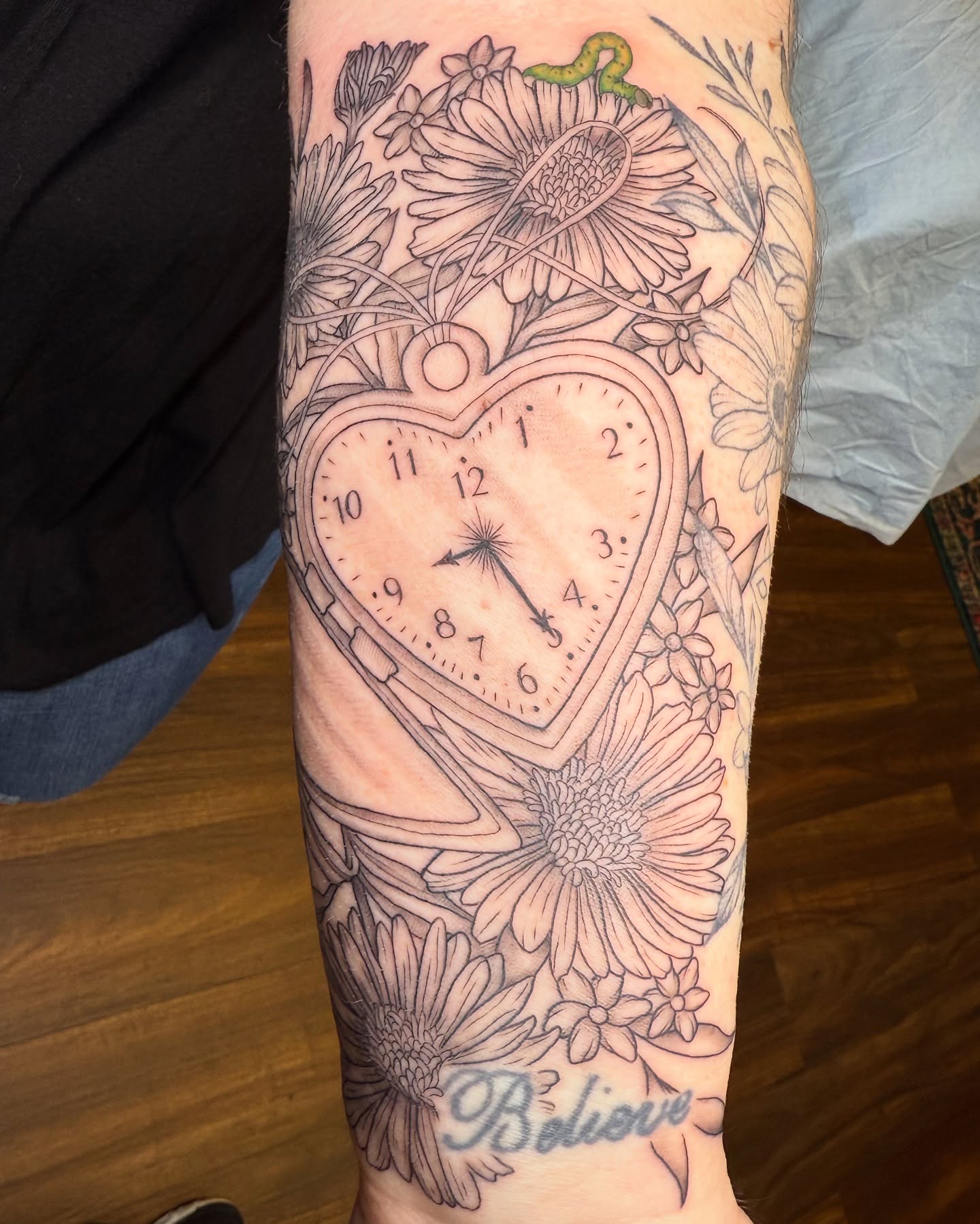Heart-shaped clock black and grey tattoo on the forearm by Sania Marquez