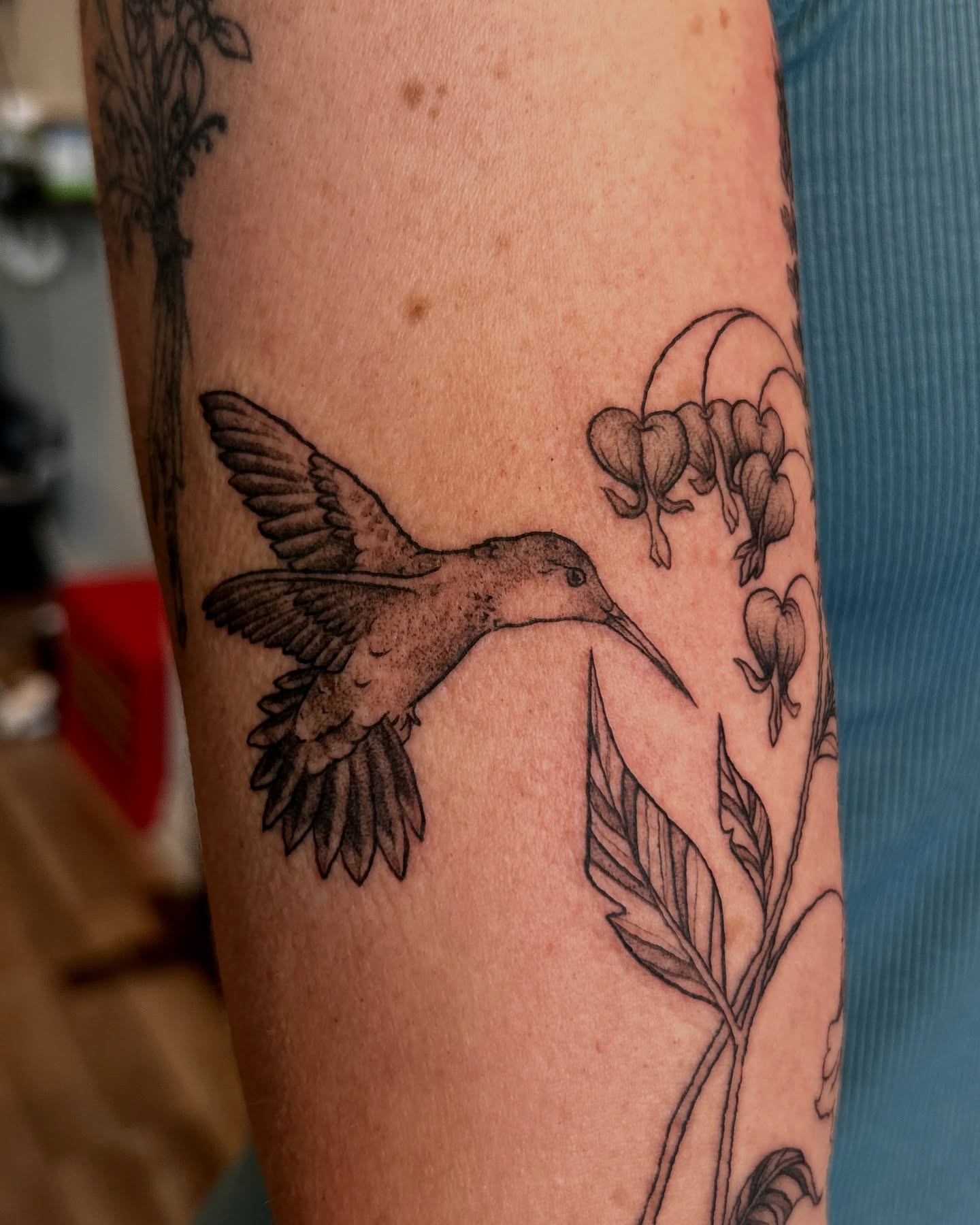 Hummingbird and flowers black and grey tattoo on the forearm by King By Trade 👑