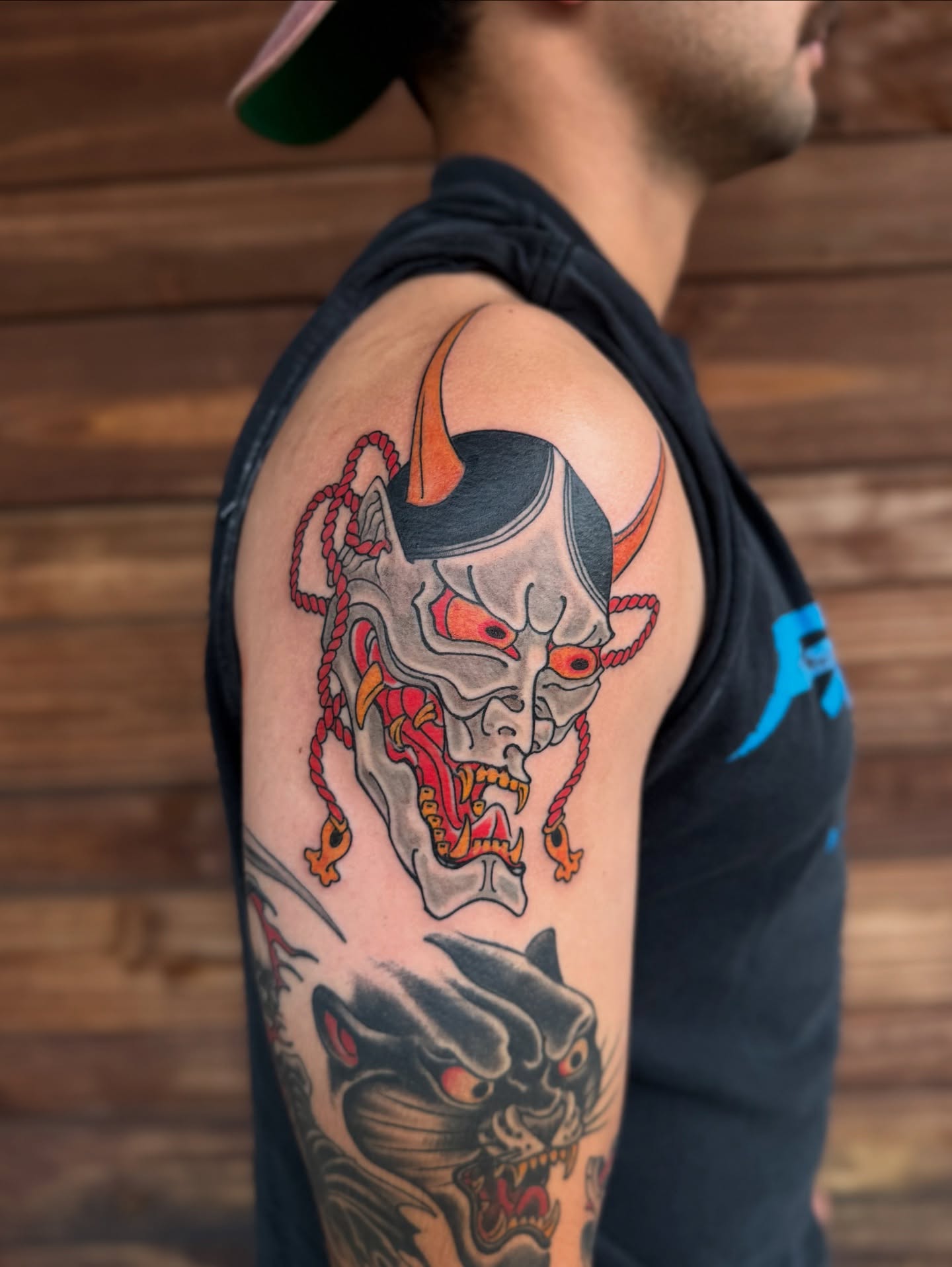 Demon mask American traditional tattoo on the upper arm by Scott Kulikowski