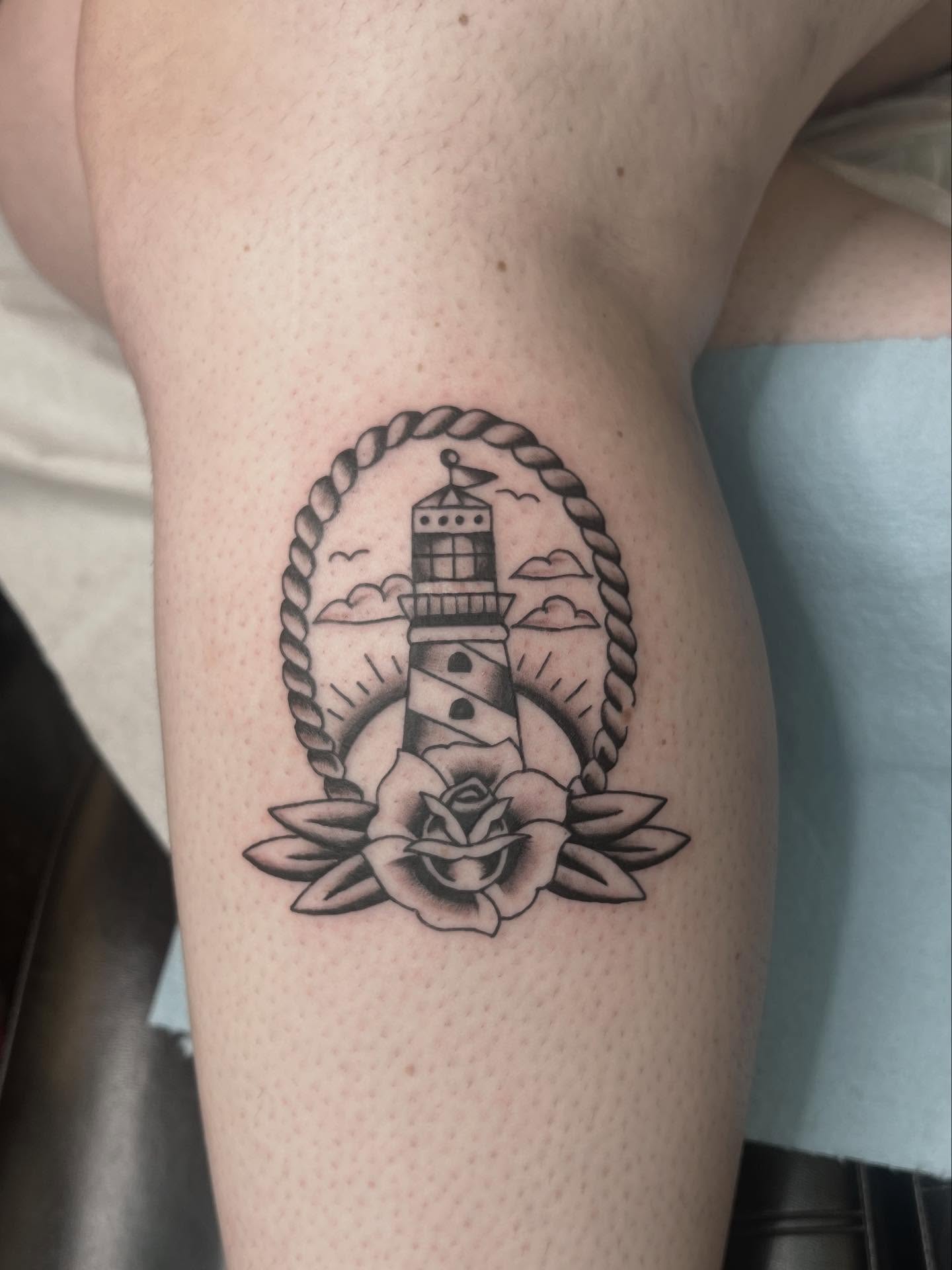 Lighthouse and rose American traditional tattoo on the thigh by Erika Donn, Portland, Oregon