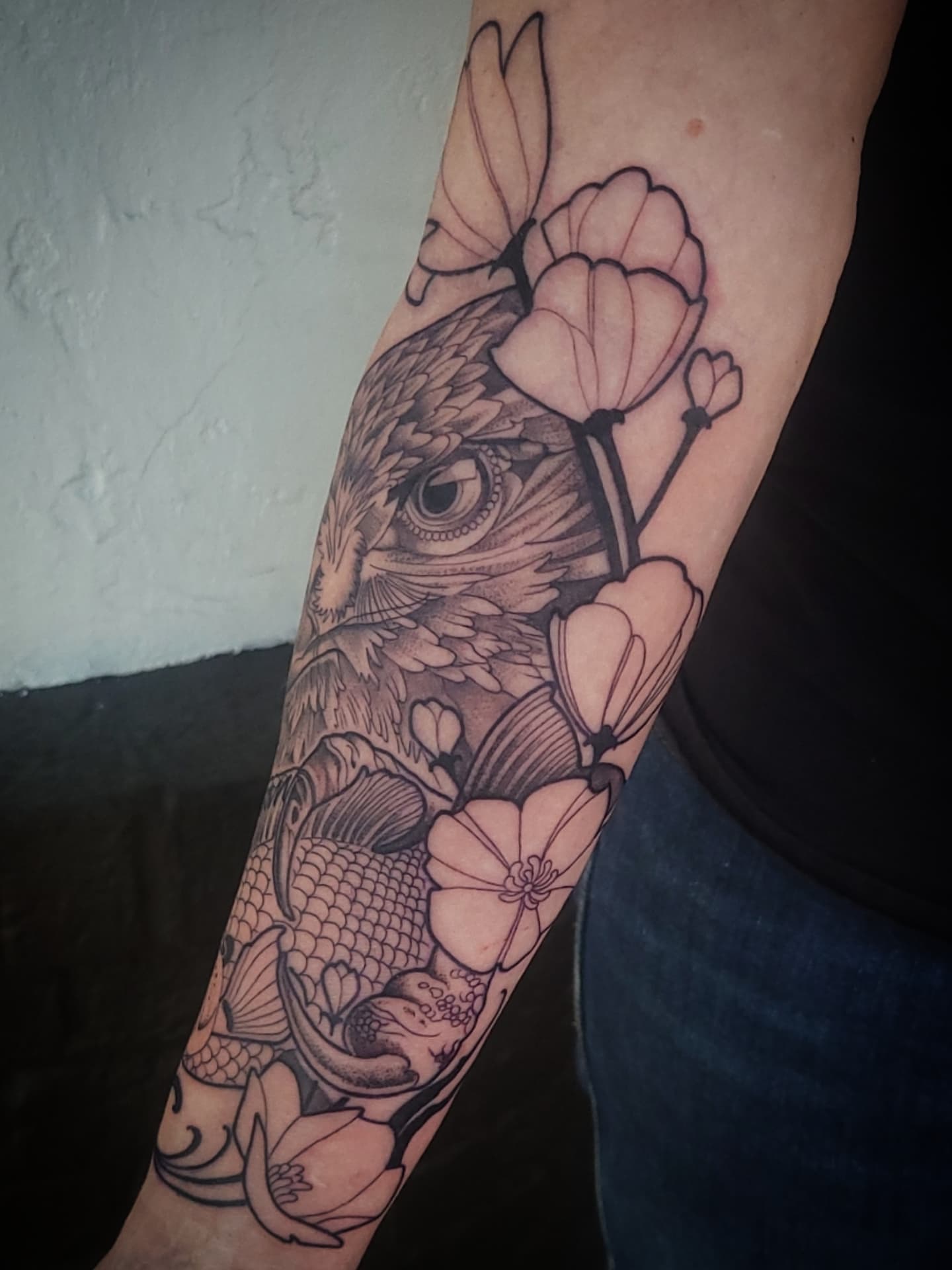 Fish and flowers realism tattoo on the forearm by Sean Hollinger