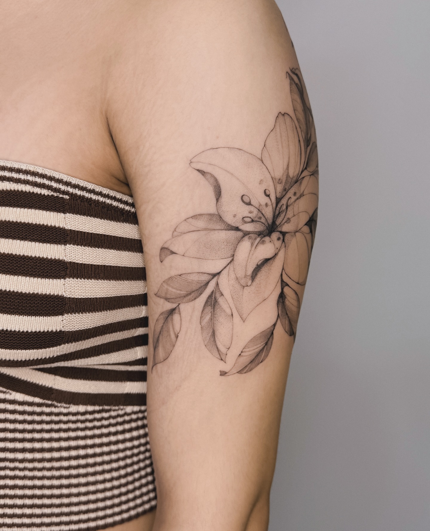 Lily dotwork tattoo on the upper arm by Blackwork & microrealism tattoos
