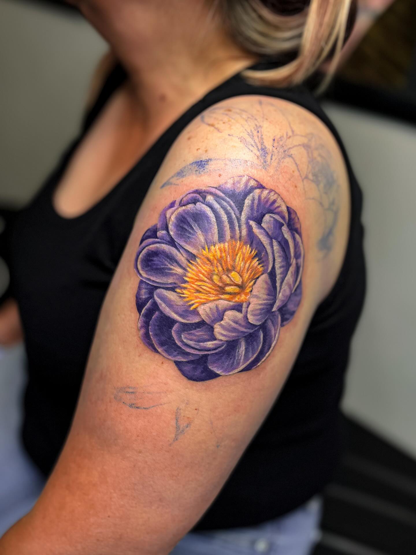 Purple flower realism tattoo on the shoulder by Katlyne Jones