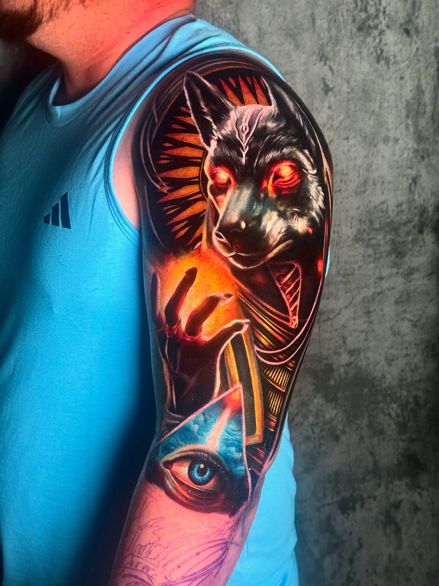 Wolf and eye dark realism tattoo on the upper arm by Ranger Rodriguez