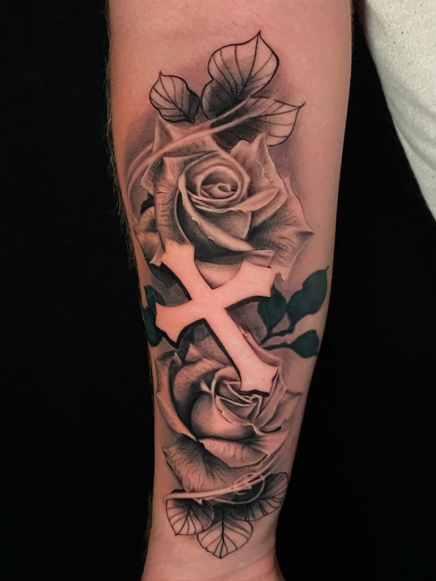 Cross and roses realism tattoo on the forearm by Brandon Bowie