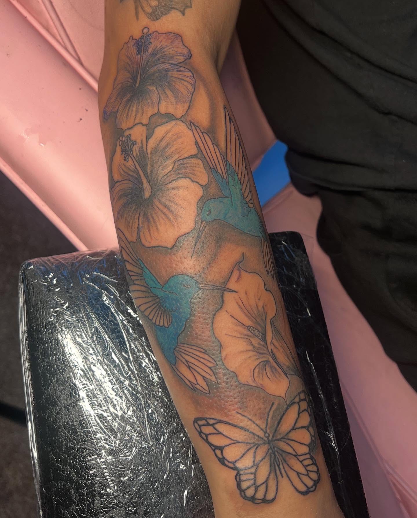 Hibiscus flowers and hummingbirds realism tattoo on the forearm by Tatted By Layy