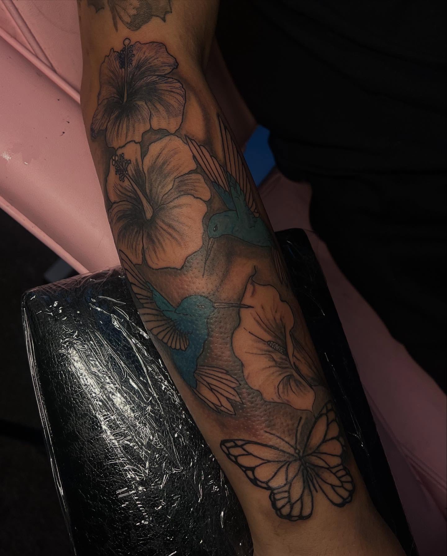 Hibiscus flowers and hummingbird realism tattoo on the forearm by Tatted By Layy