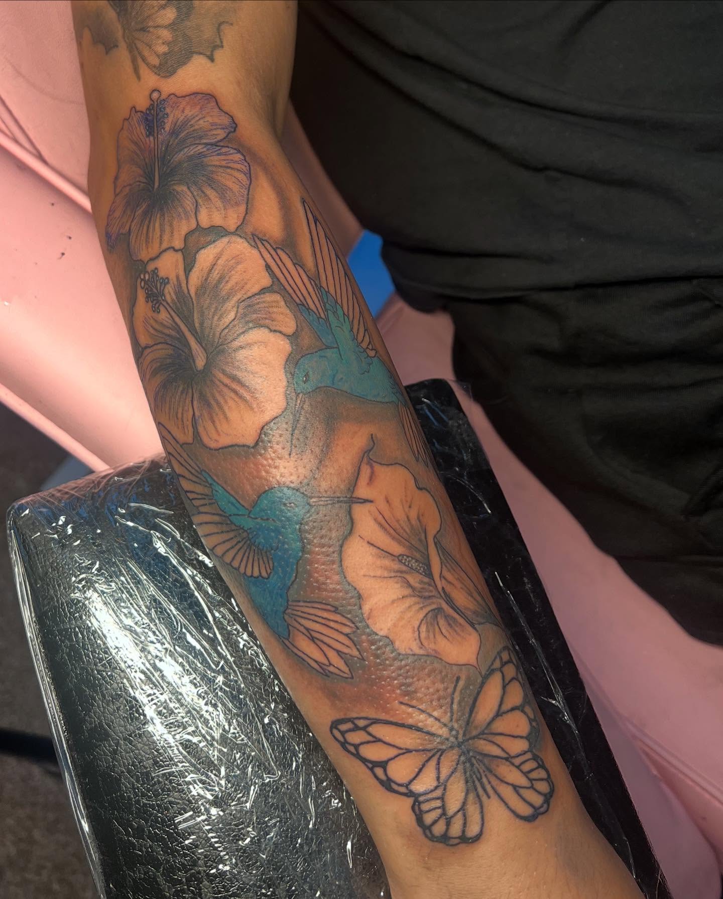 Hibiscus flowers and butterflies realism tattoo on the forearm by Tatted By Layy