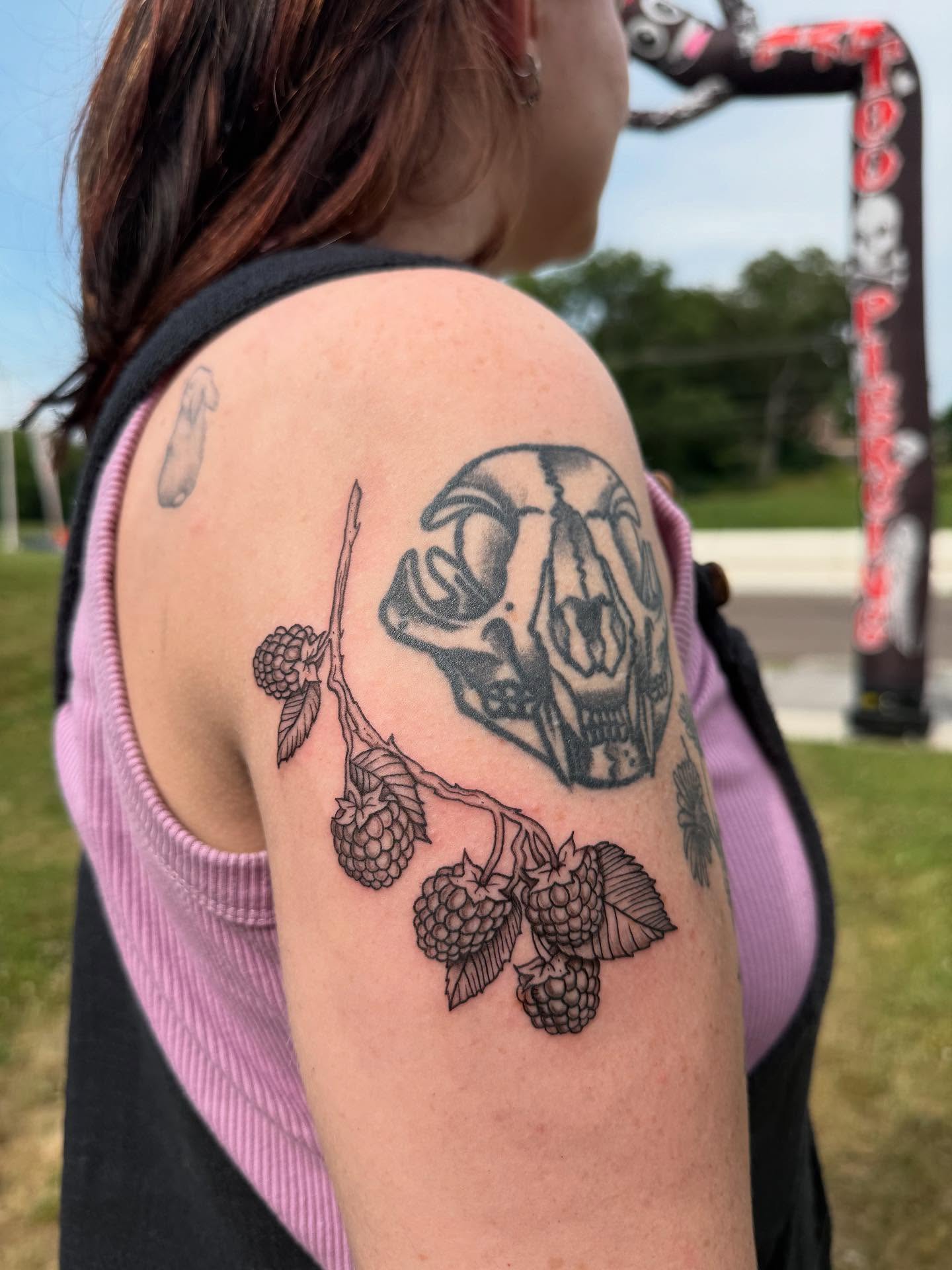 Skull and raspberries black and grey tattoo on the shoulder by Imani