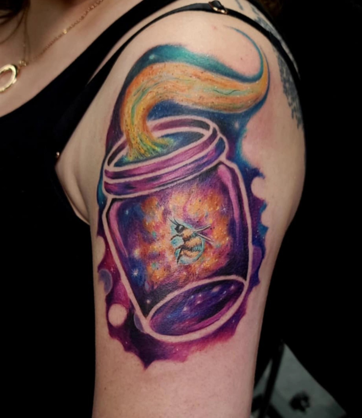 Galaxy in jar watercolor tattoo on the upper arm by Drew King