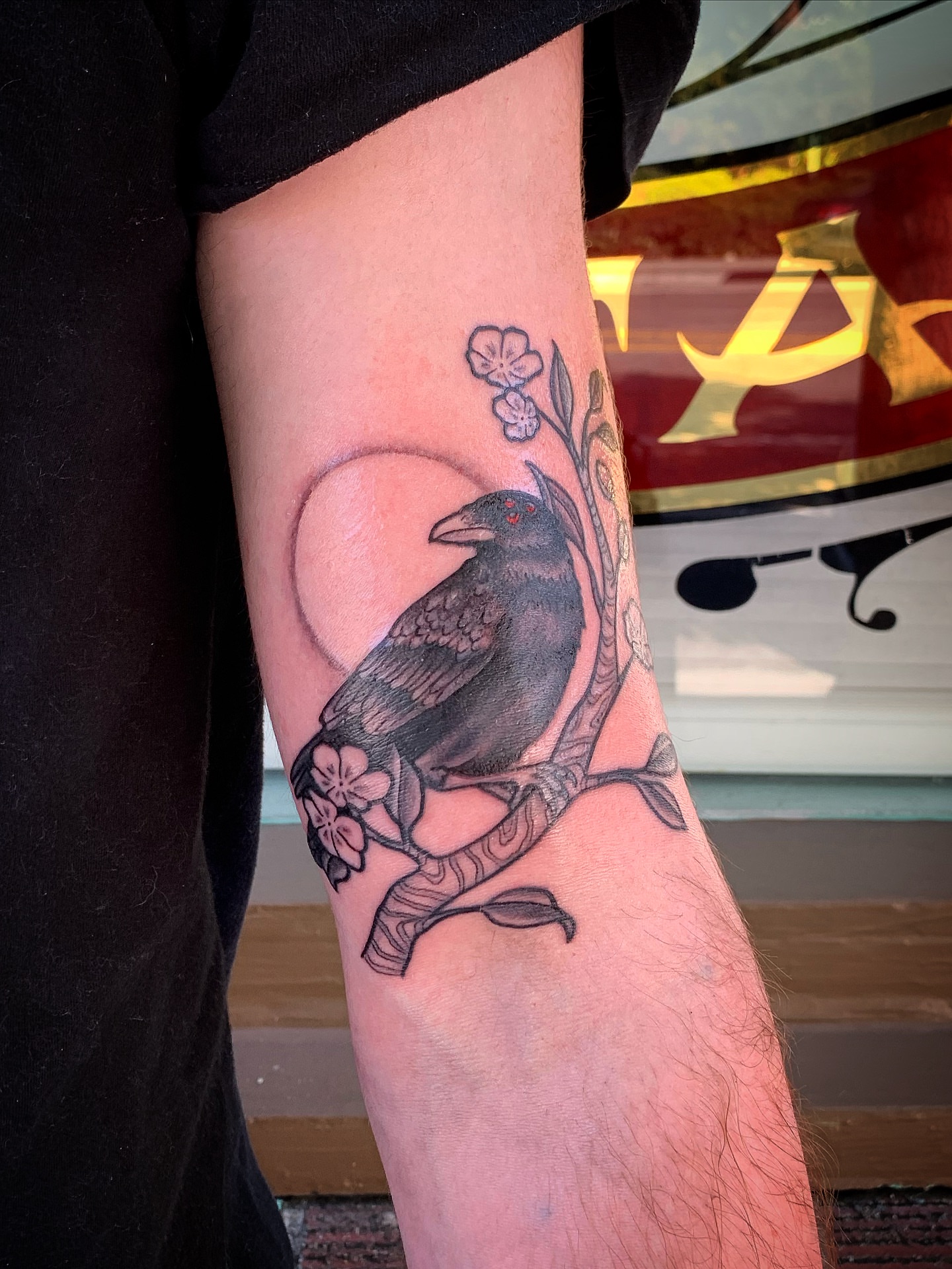 Crow and cherry blossoms black and grey tattoo on the forearm by Laura