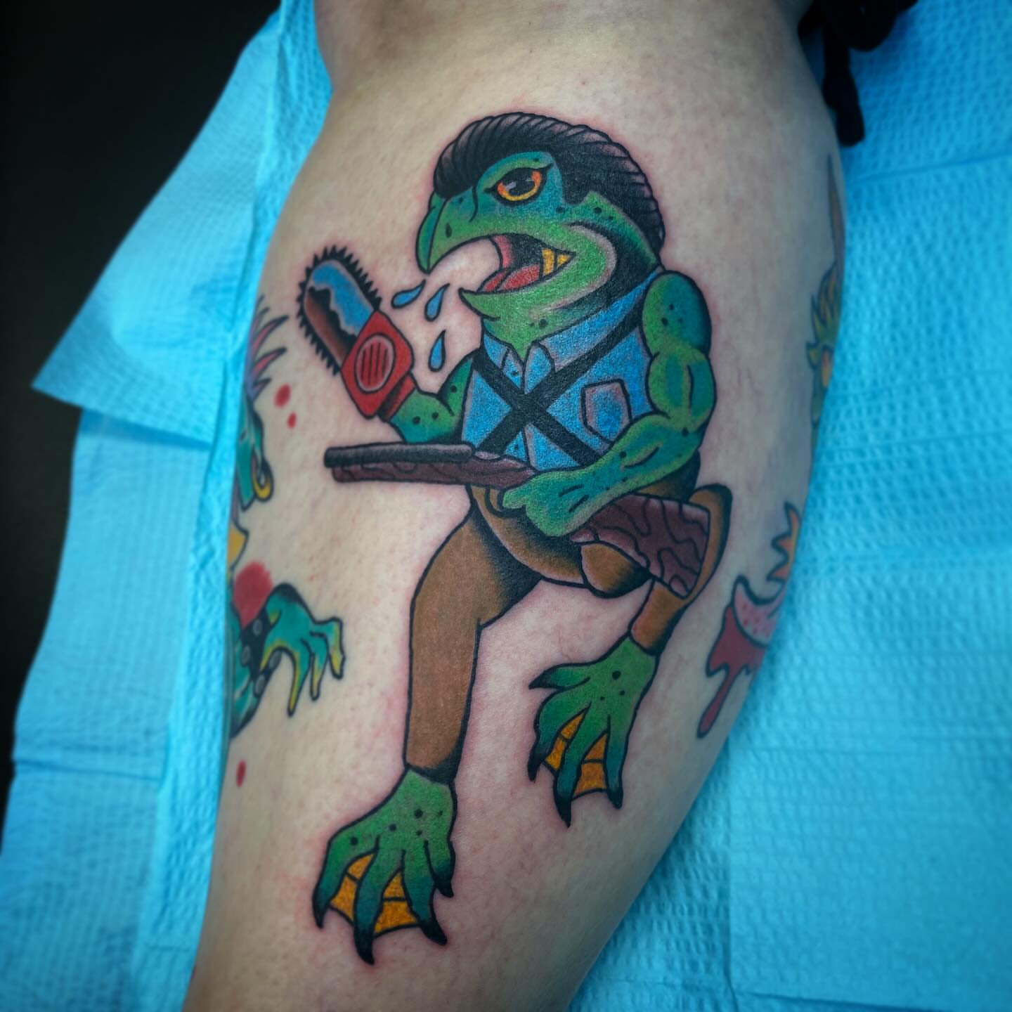 Frog with chainsaw American traditional tattoo on the thigh by Kyle Mitchell, Cincinnati