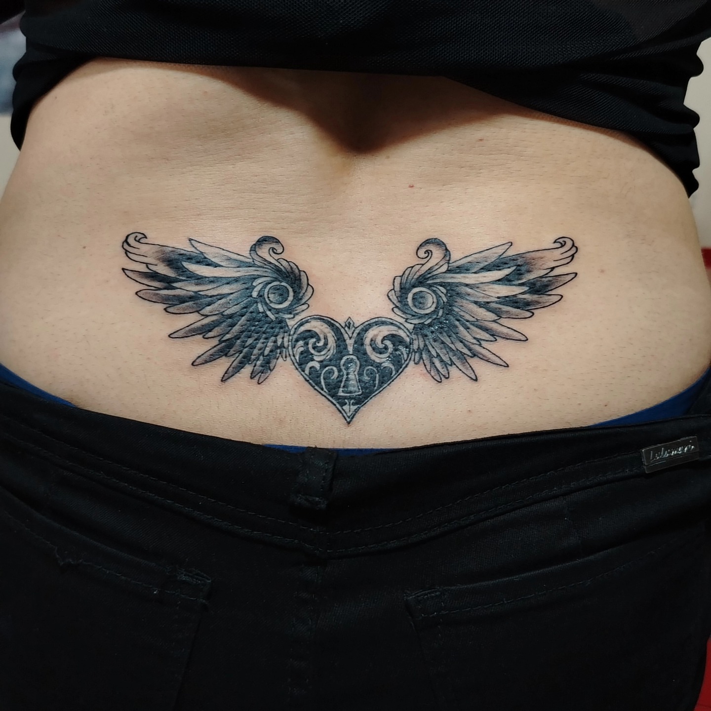 Wings and heart black and grey tattoo on the torso by Alexander Tattooink