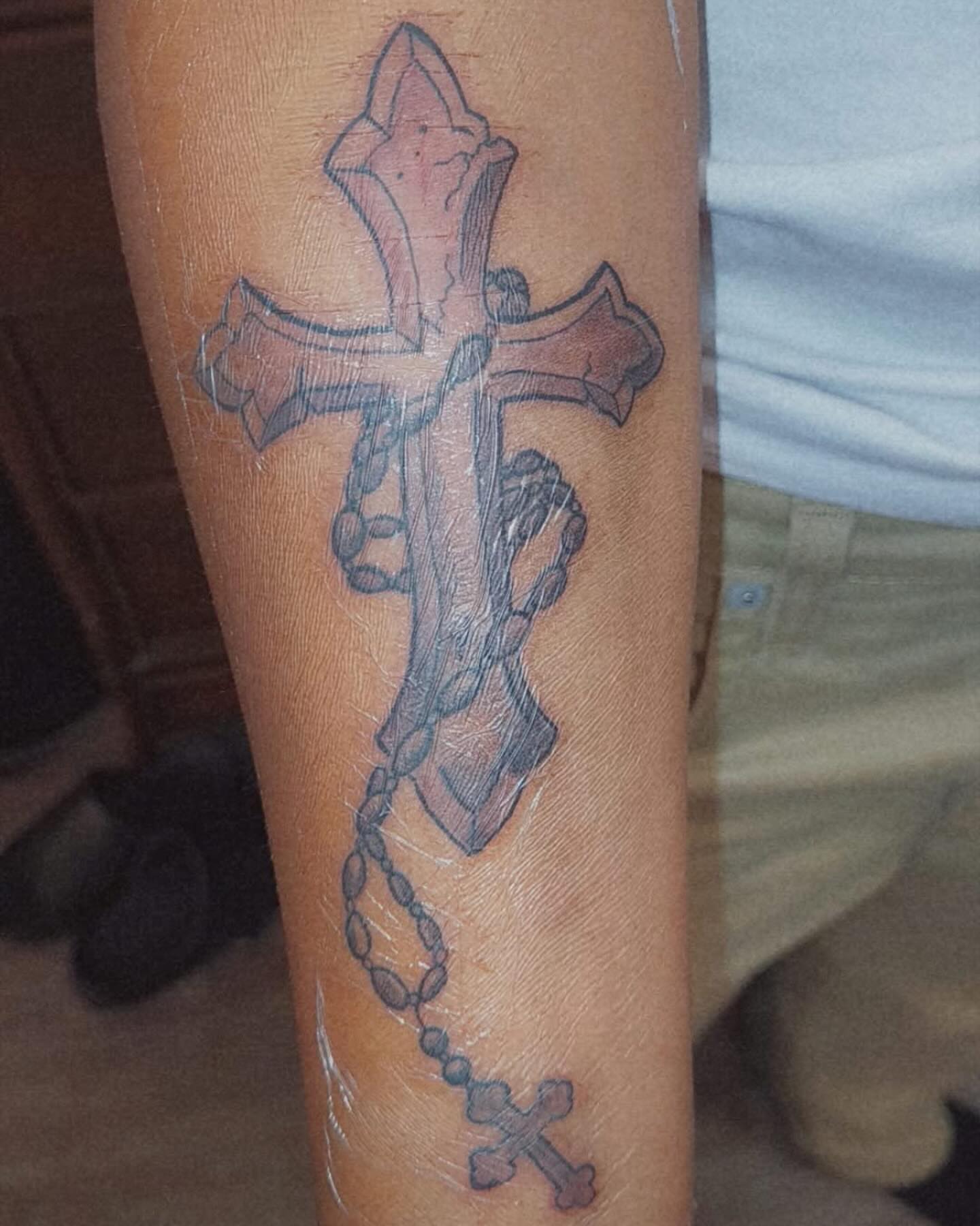 Cross with rosary black and grey tattoo on the forearm by Bris