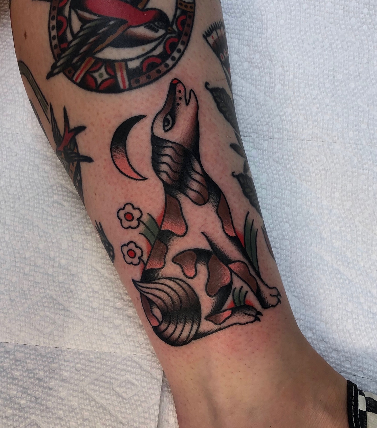 Wolf and crescent moon American traditional tattoo on the forearm by EVA Traditional Tattoos