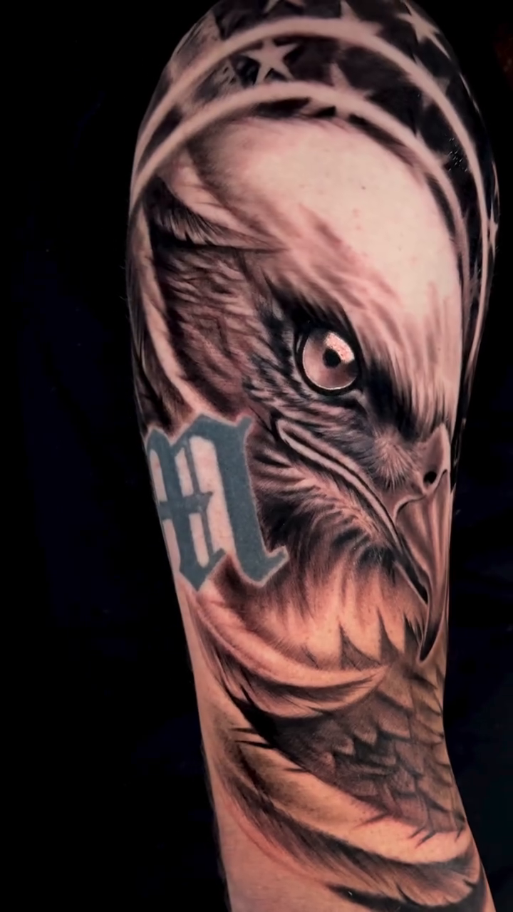 Eagle head with letter M realism tattoo by Katie Jones