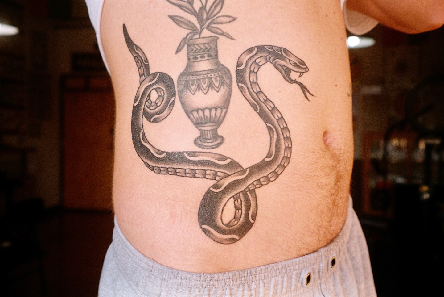 Snake and vase black and grey tattoo on the ribs by Téa Fish