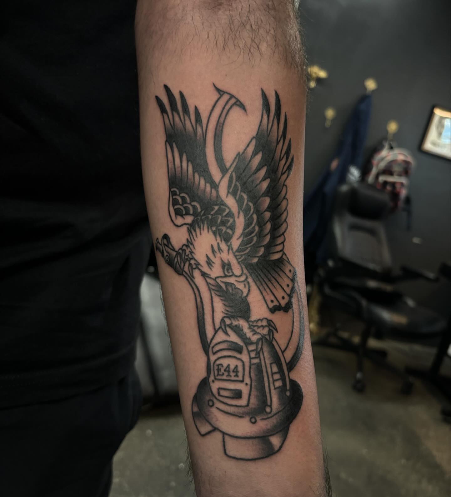 Firefighter helmet with phoenix realism tattoo on the forearm by Brett Ferguson