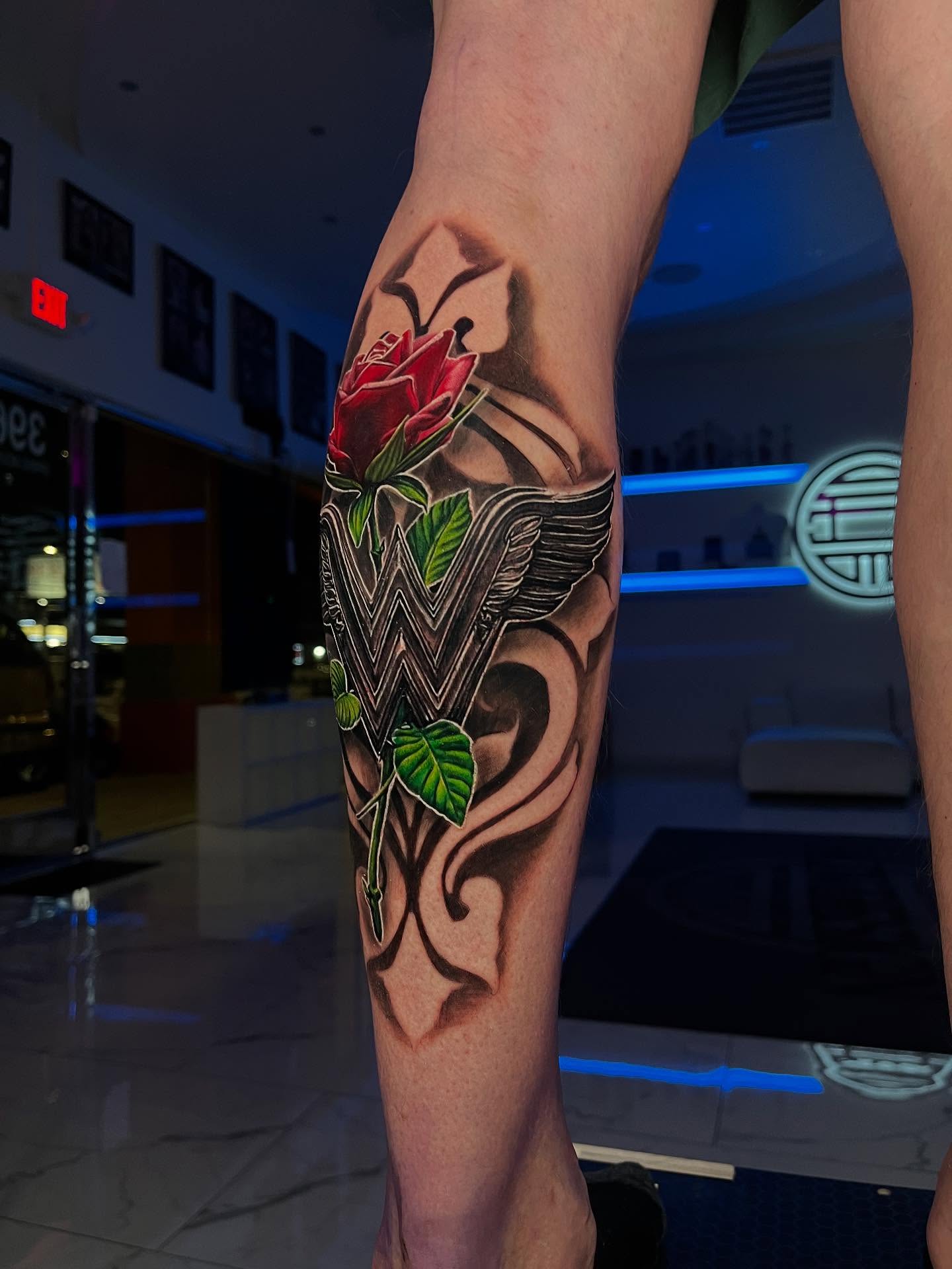 Wonder woman logo with rose realism tattoo on the calf by Stacy Lavette