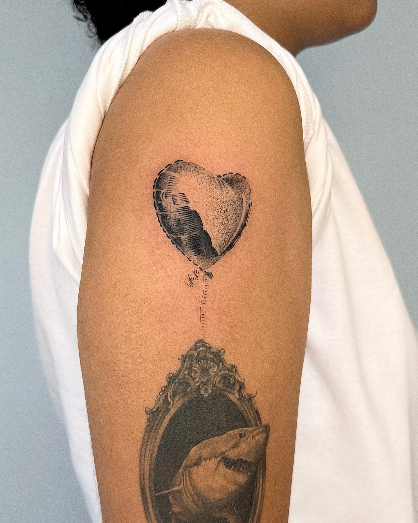 Heart balloon shark realism tattoo on the upper arm by Jenni Palomaa