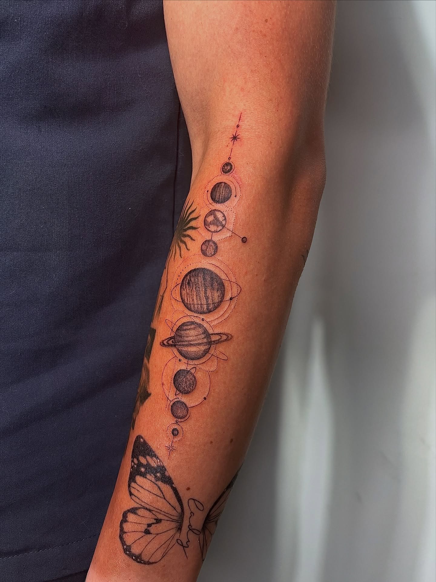 Planets and butterfly dotwork tattoo on the forearm by @tattotos