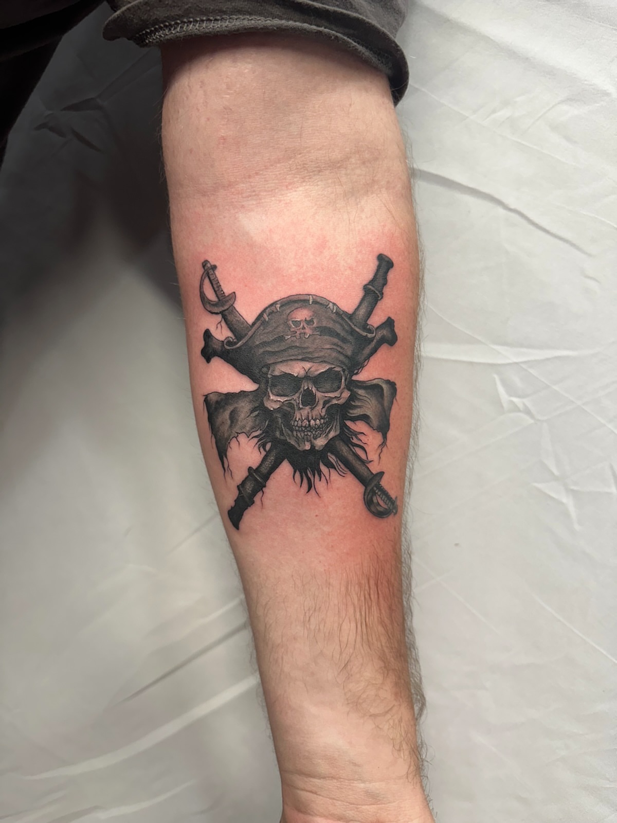 Pirate skull and swords realism tattoo on the forearm by Elizabeth’s Eclectic Tattoos