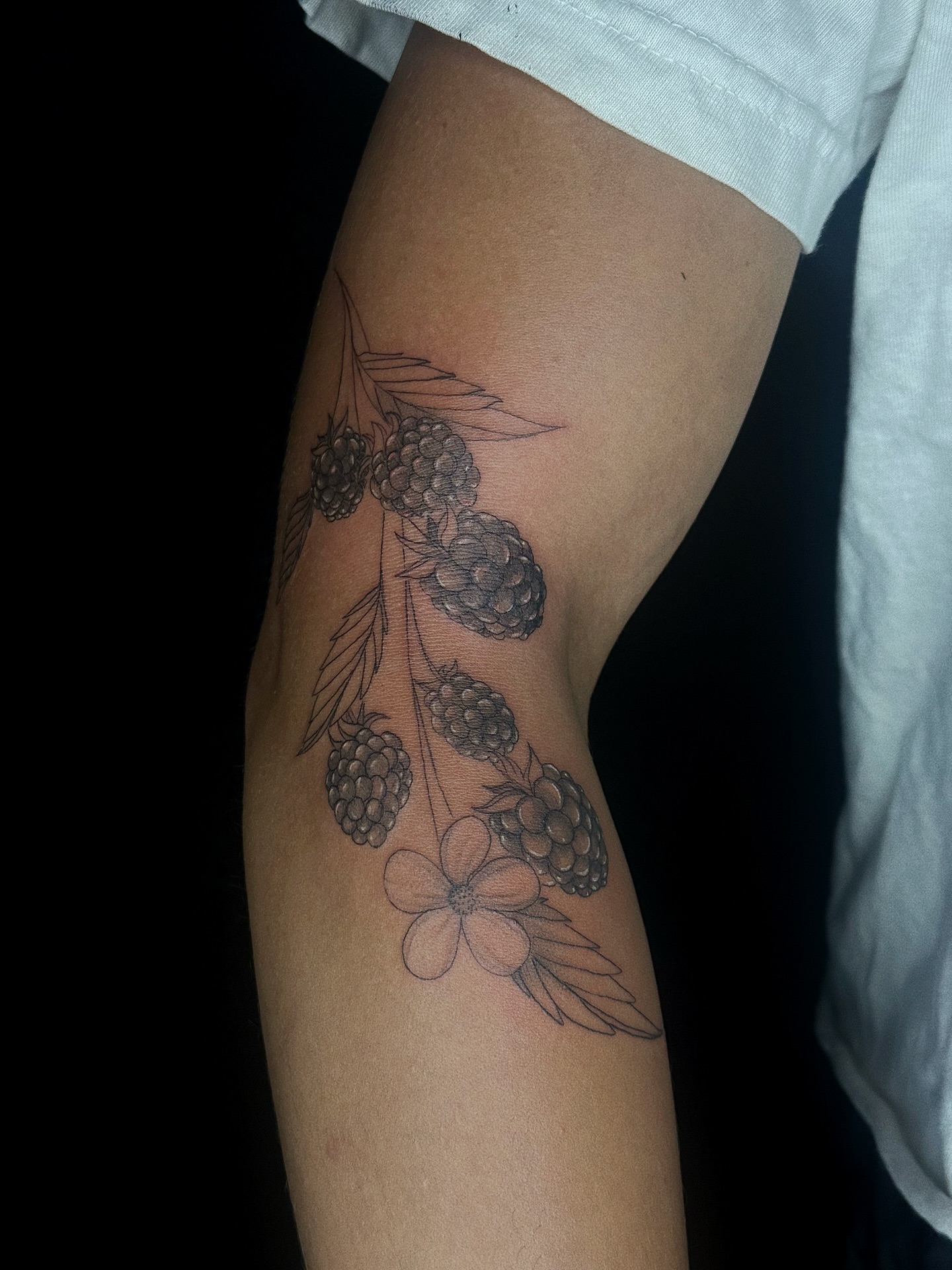 Raspberries and flower black and grey tattoo on the forearm by elena