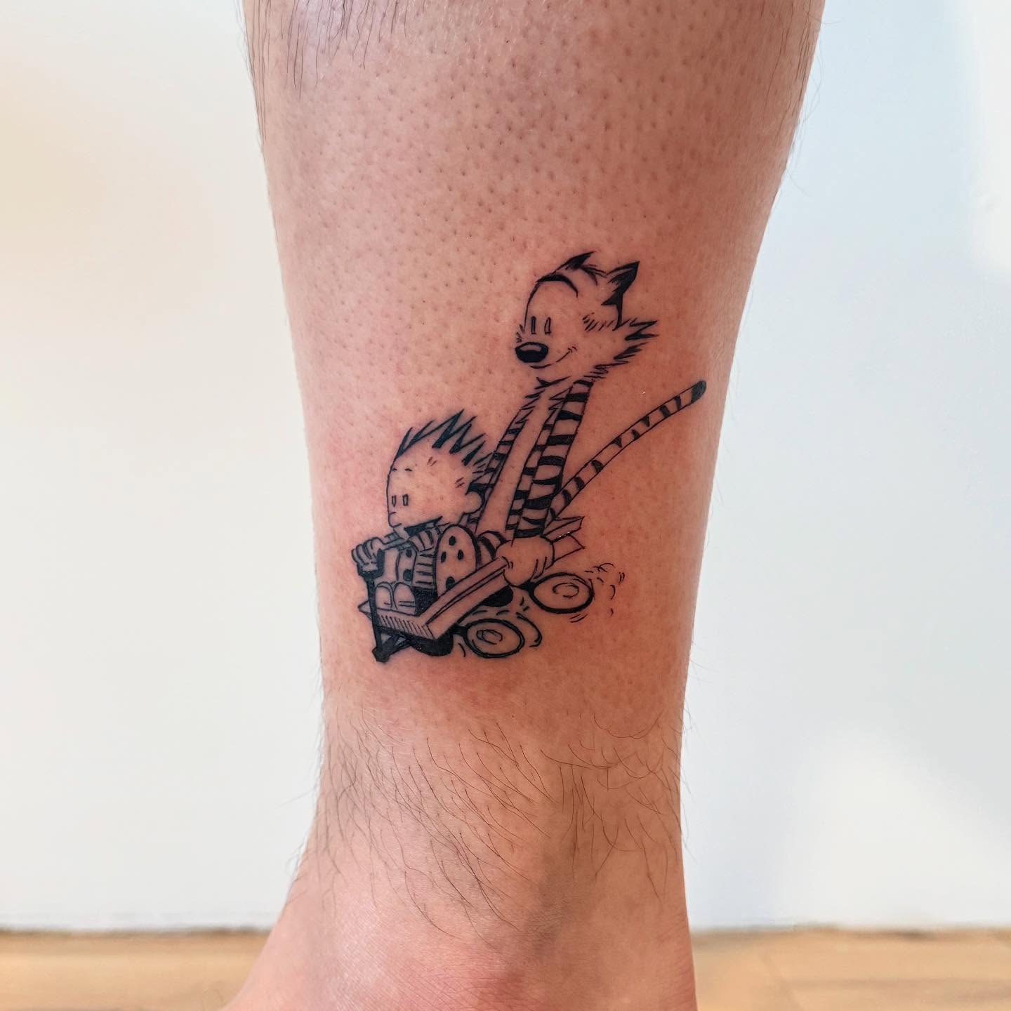Calvin and hobbes black and grey tattoo on the calf by Kirsten