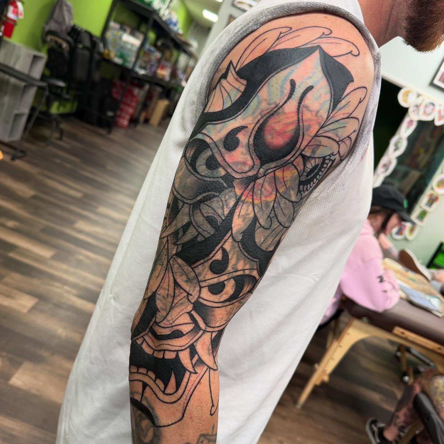 Floral skull black and grey tattoo on the upper arm by Spencer Webb