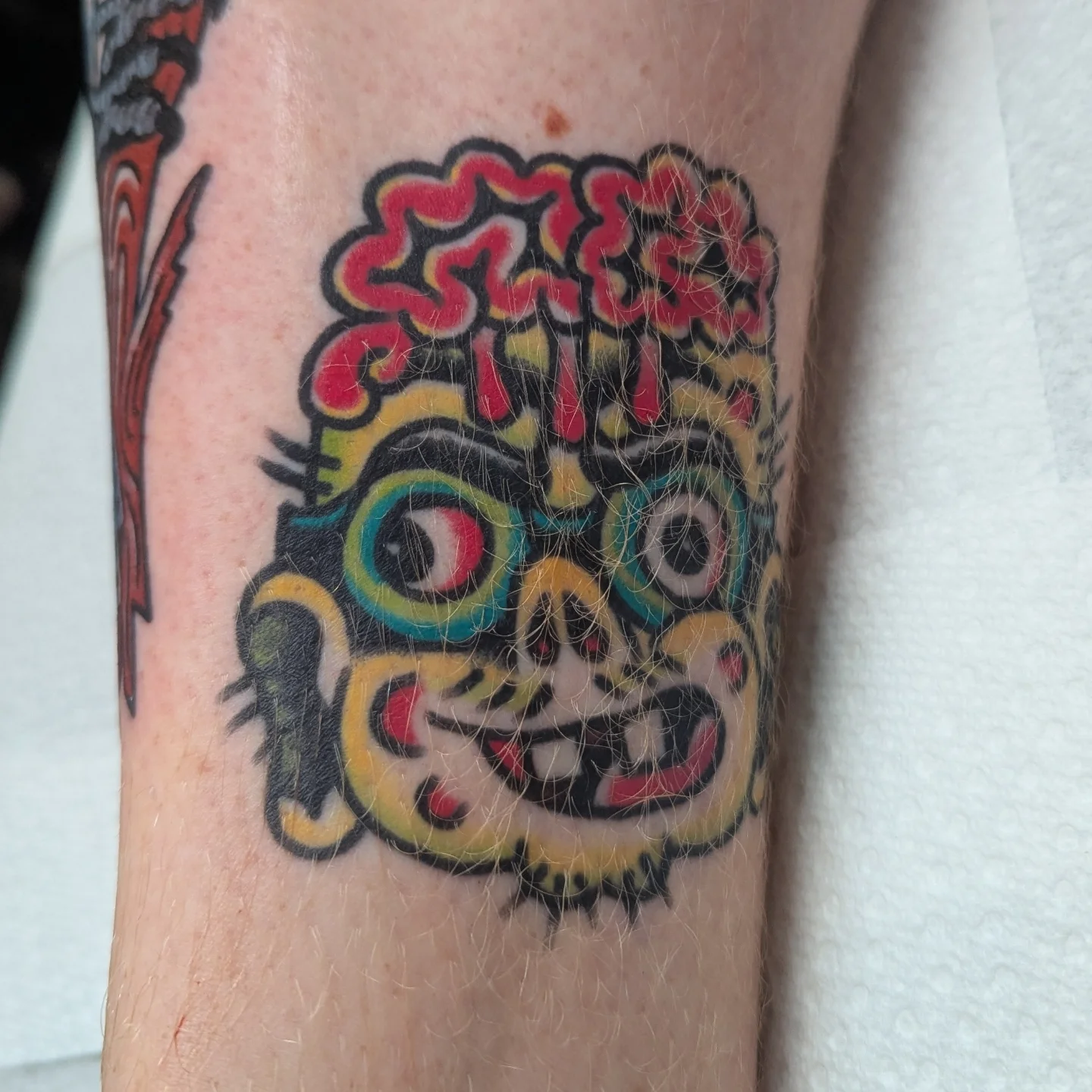 Mask American traditional tattoo on the forearm by Zack Mueller