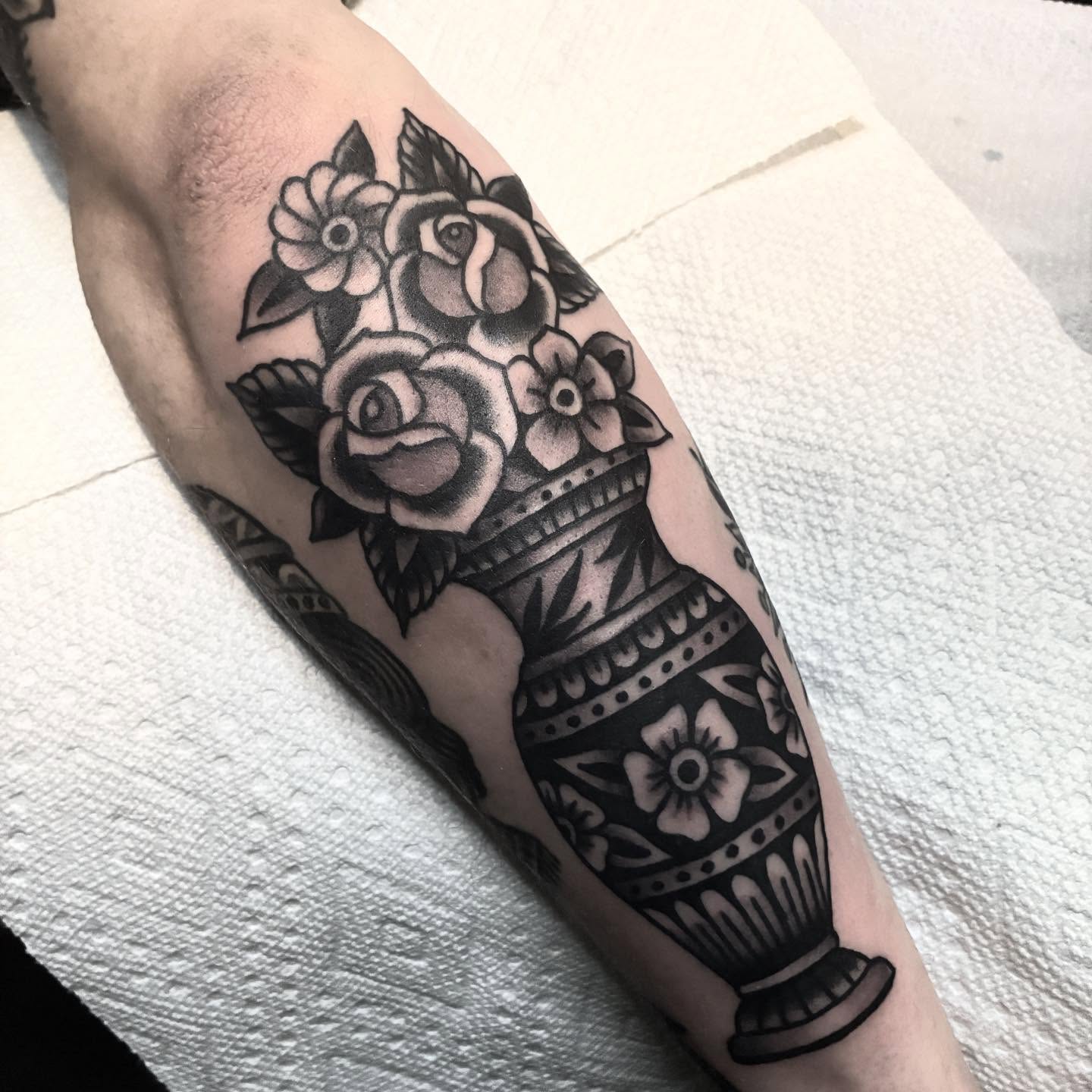 Vase with flowers black and grey tattoo on the forearm by Mike Hudgins