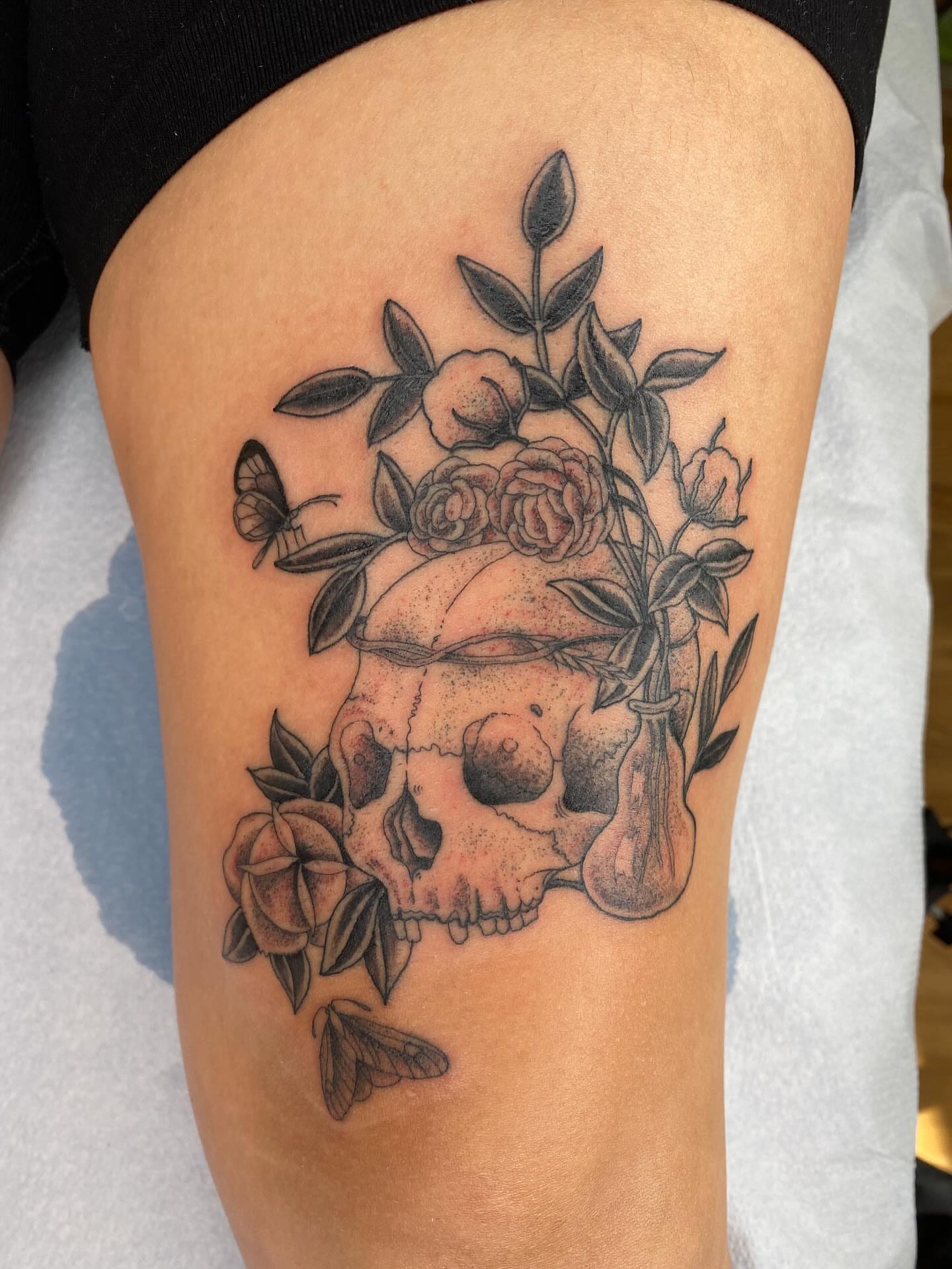 Skull and roses dotwork tattoo on the thigh by Finley Jordan