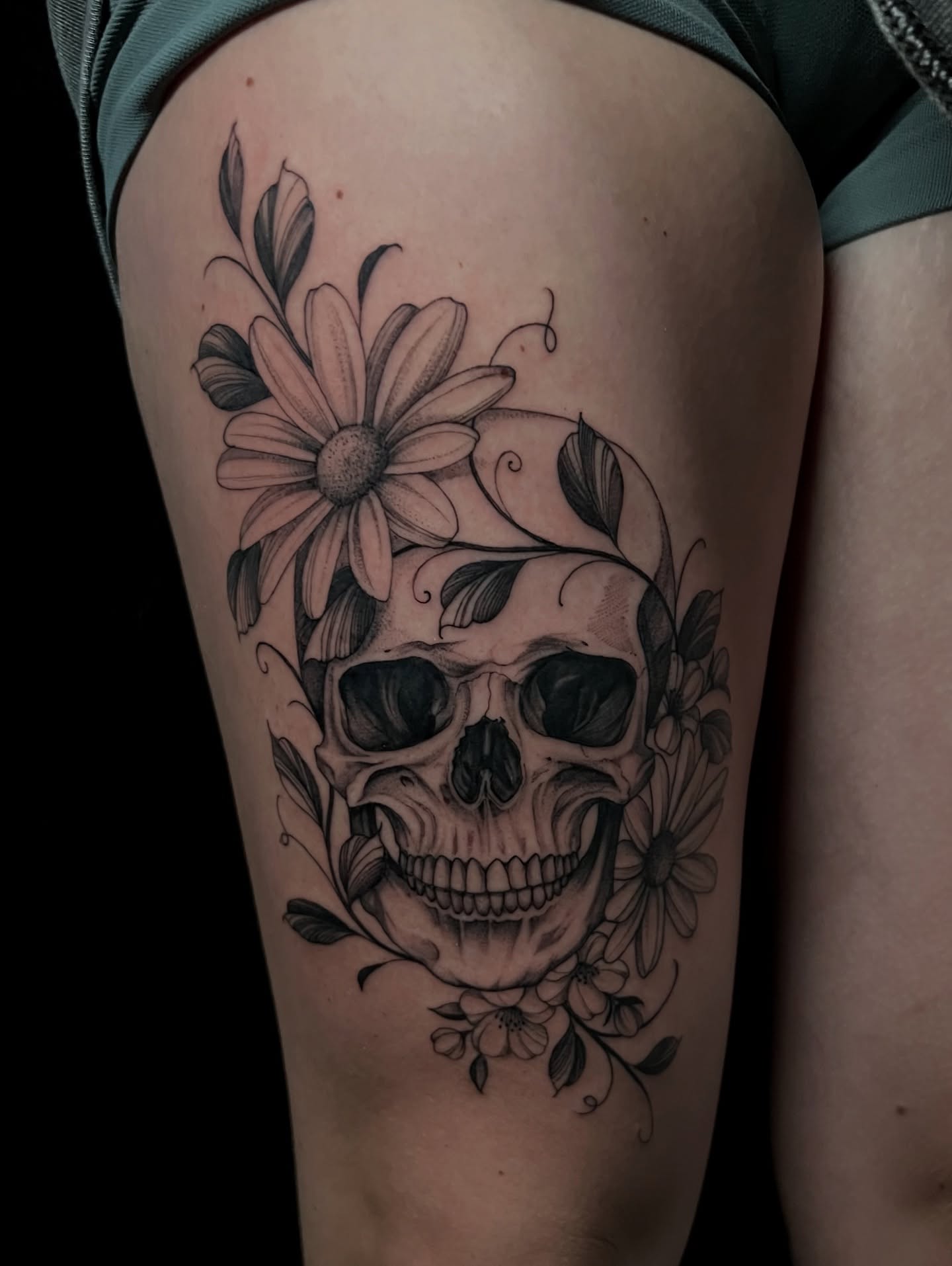 Skull and flowers realism tattoo on the thigh by Chelsea Speirs