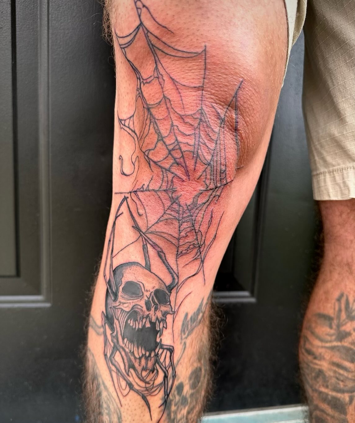 Spiderweb and skull black and grey tattoo on the calf by Mika'la Berry