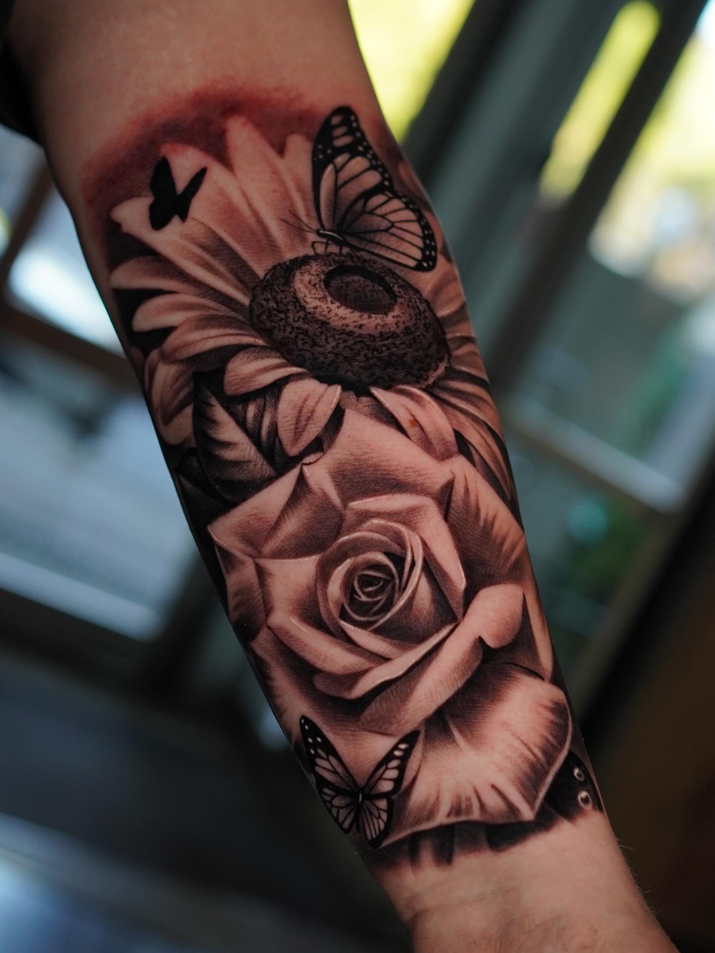 Sunflower and rose realism tattoo on the forearm by Jesse Missman