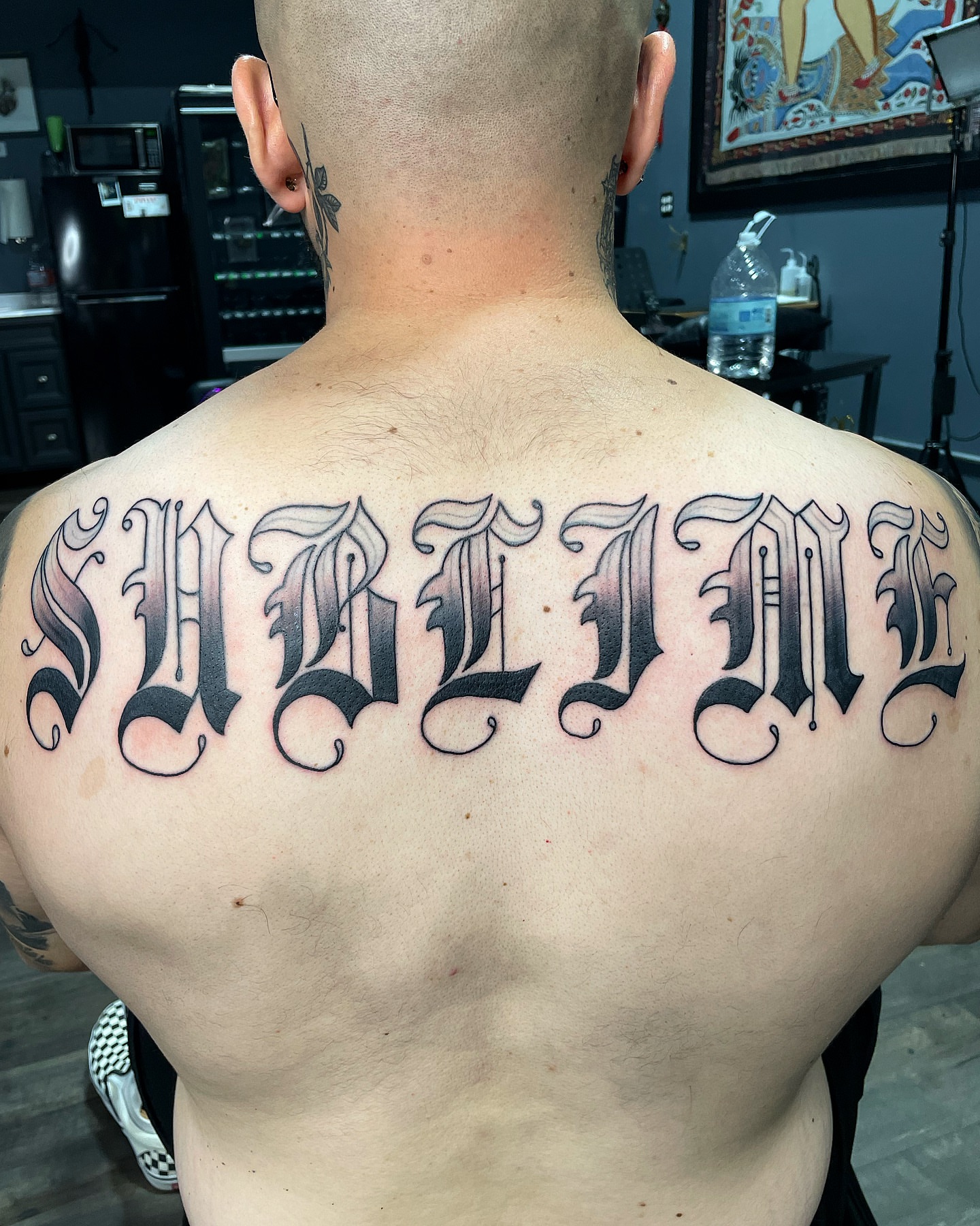 Sublime lettering script tattoo on the back by Alex Ortiz