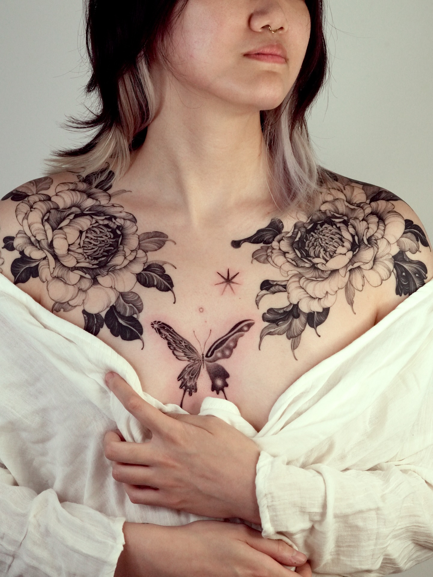 Butterfly and flowers black and grey tattoo on the chest by Stella Oh
