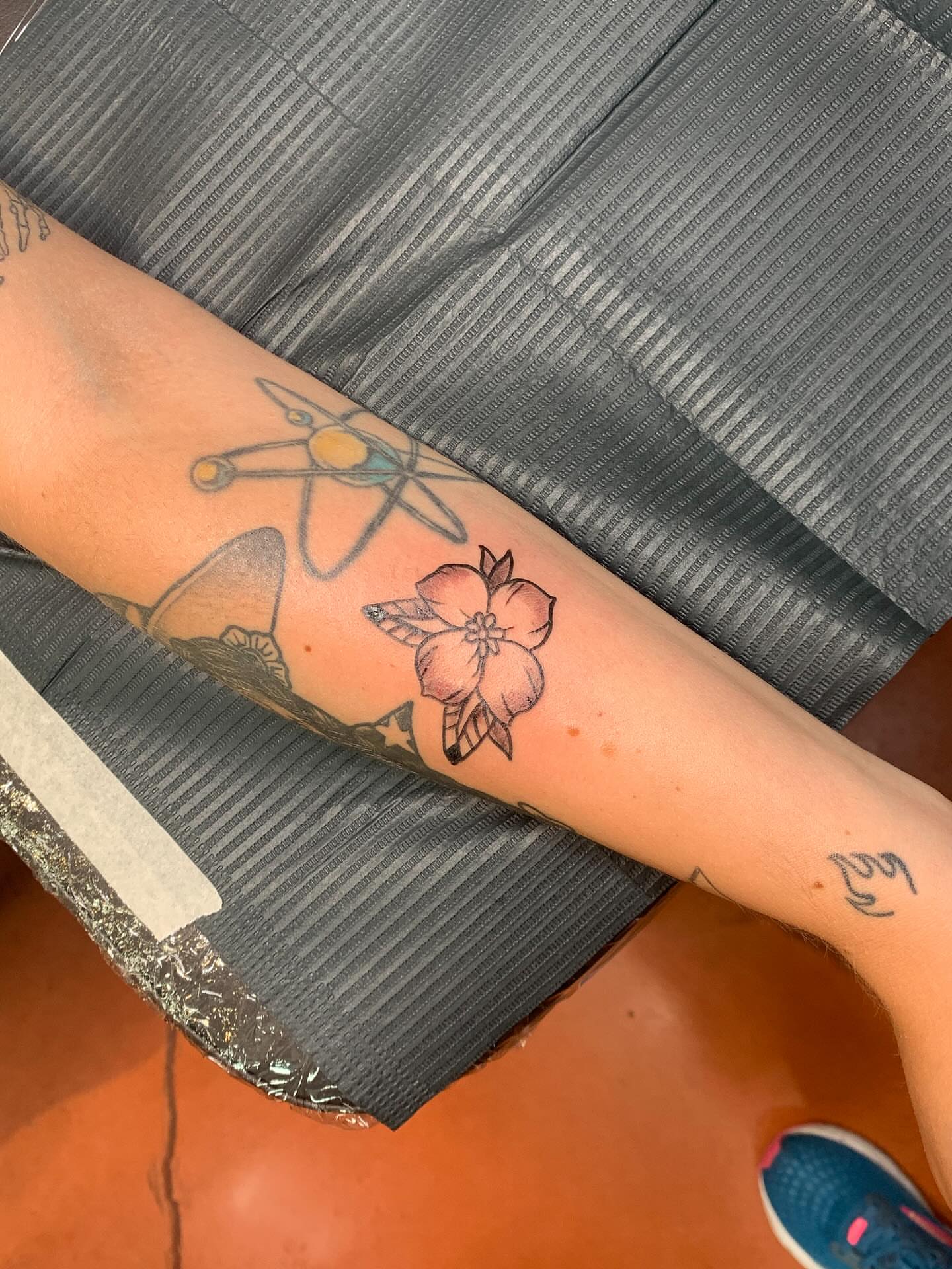 Atom and flower geometric tattoo on the forearm by ellie