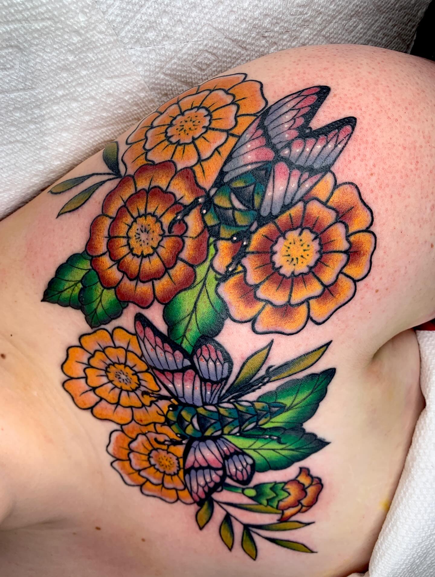 Flowers and butterflies American traditional tattoo on the shoulder by April Morris ⚔️ Tattoo Goblin