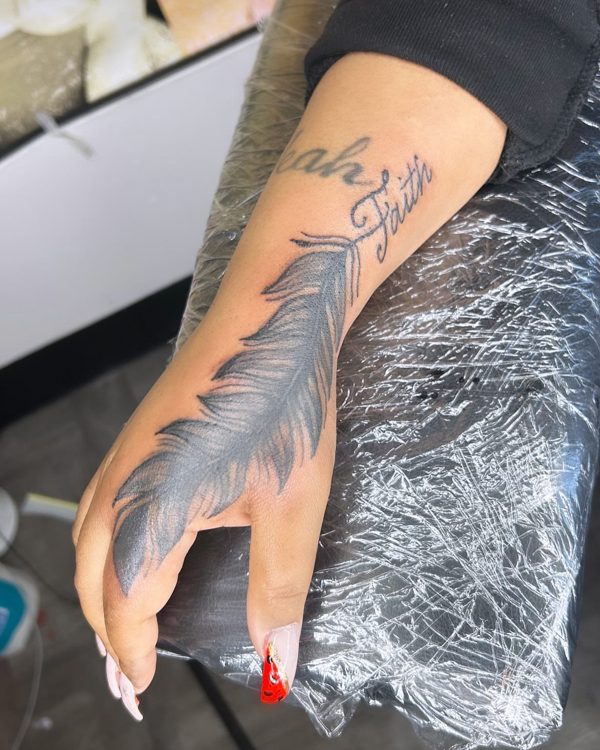 Feather black and grey tattoo on the forearm by Rell Washington, Marlow Heights, Maryland
