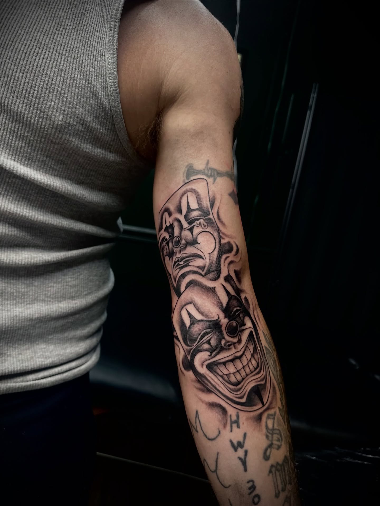 Clown black and grey tattoo on the forearm by Kassie Perian