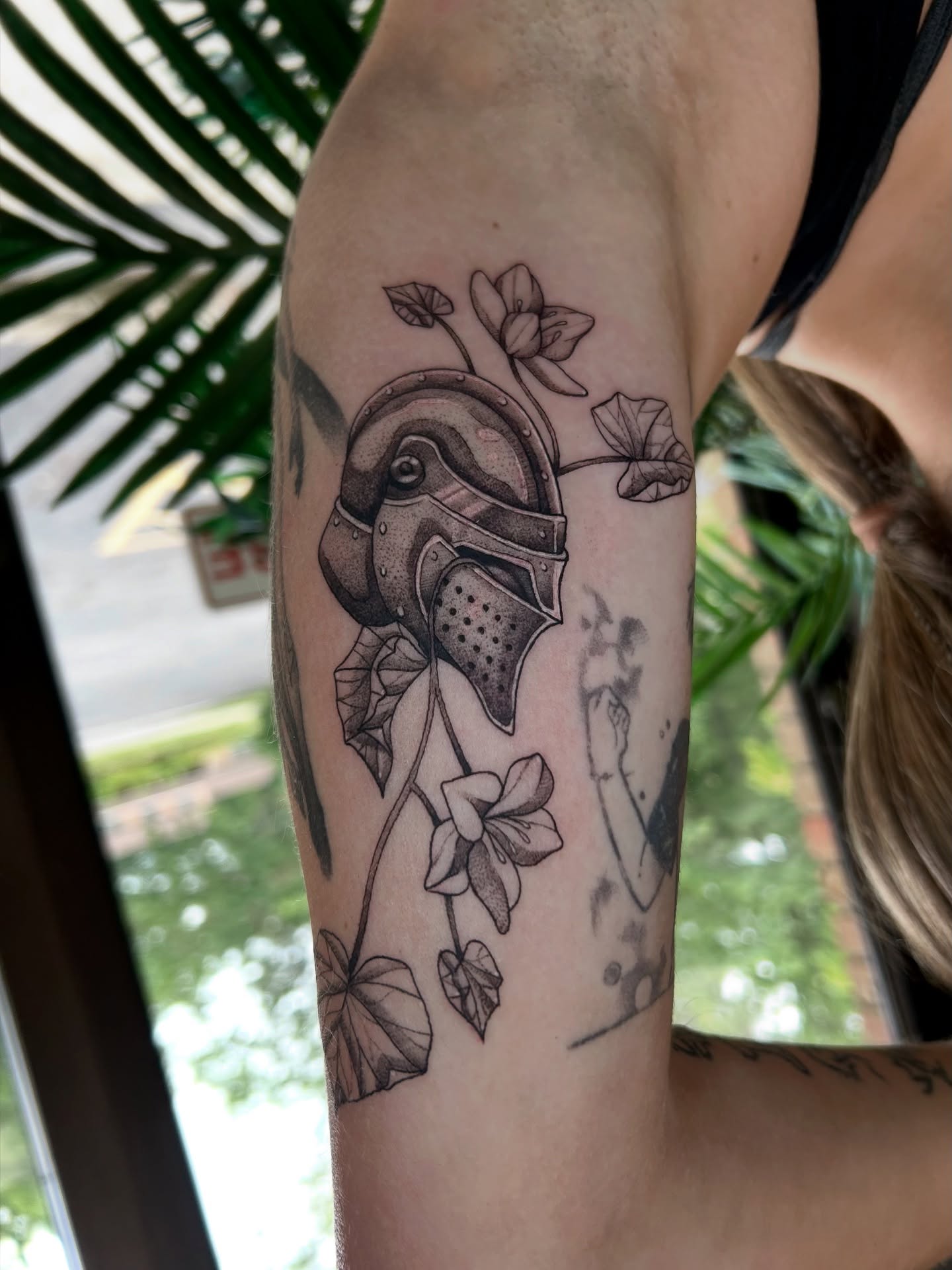Helmet with flowers black and grey tattoo on the forearm by Taylor Heidtbrink