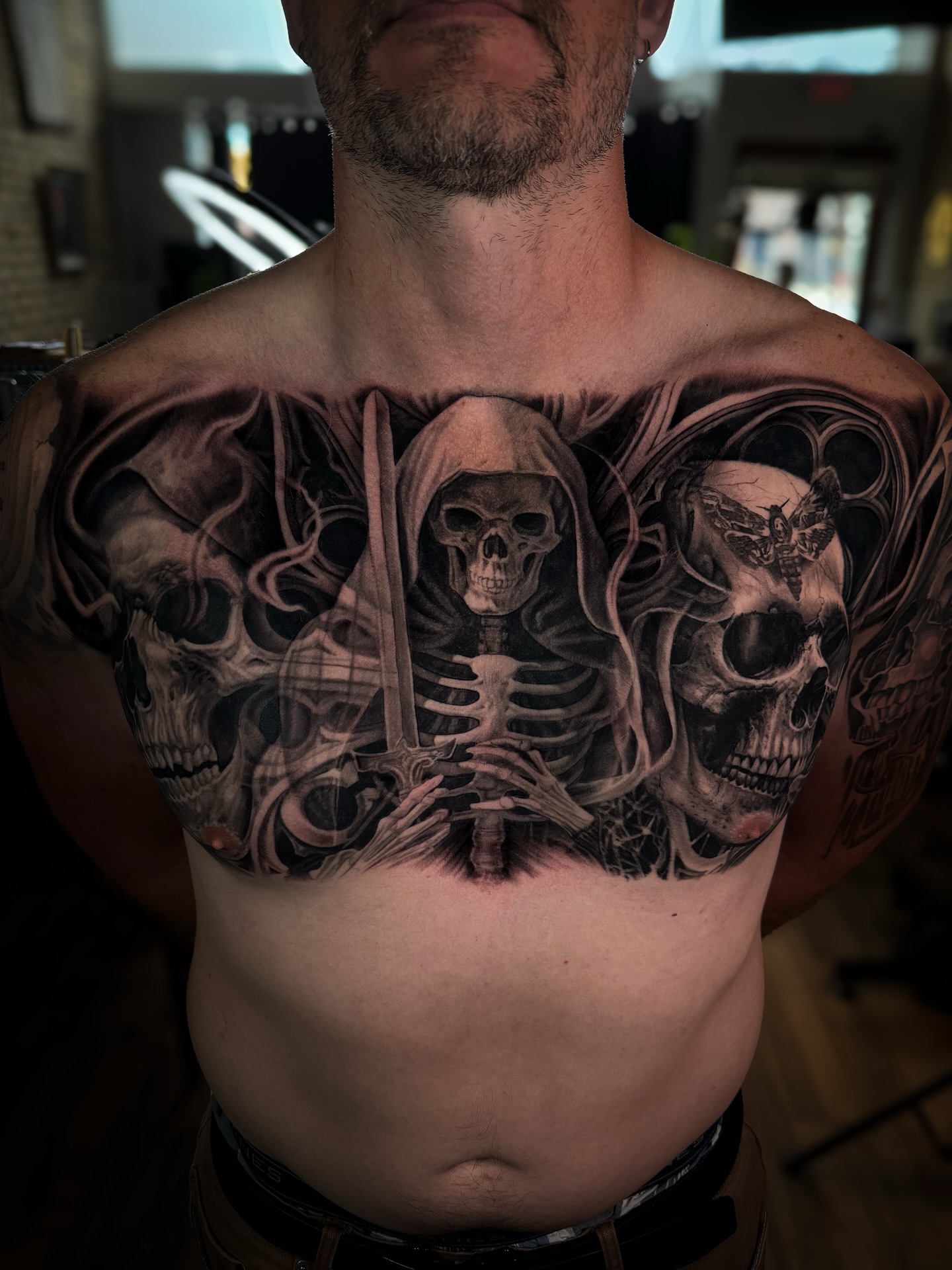 Reaper and skulls dark realism tattoo on the chest by Aaron, Milwaukee, Wisconsin