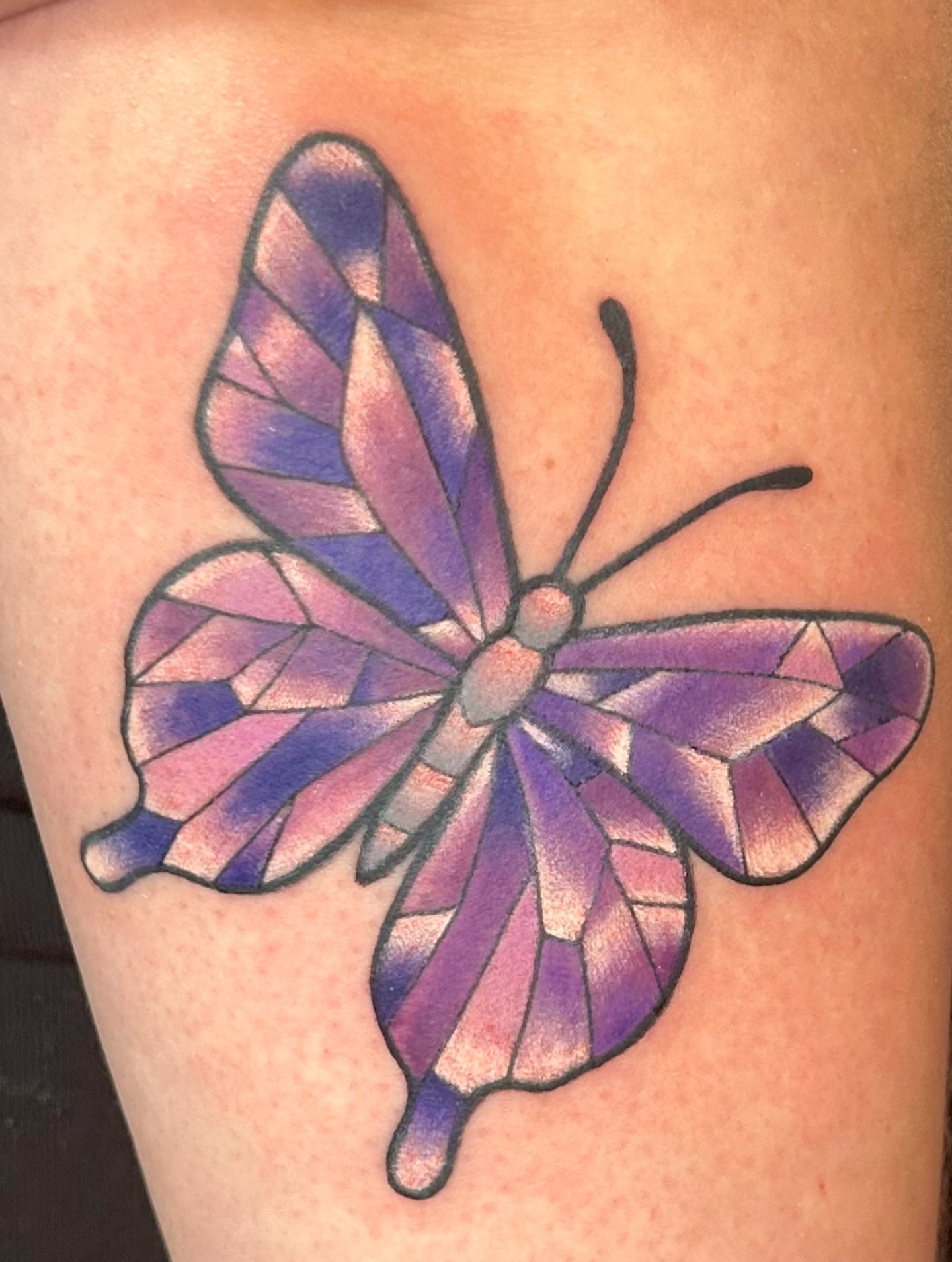 Stained glass butterfly geometric tattoo on the thigh by Mallory