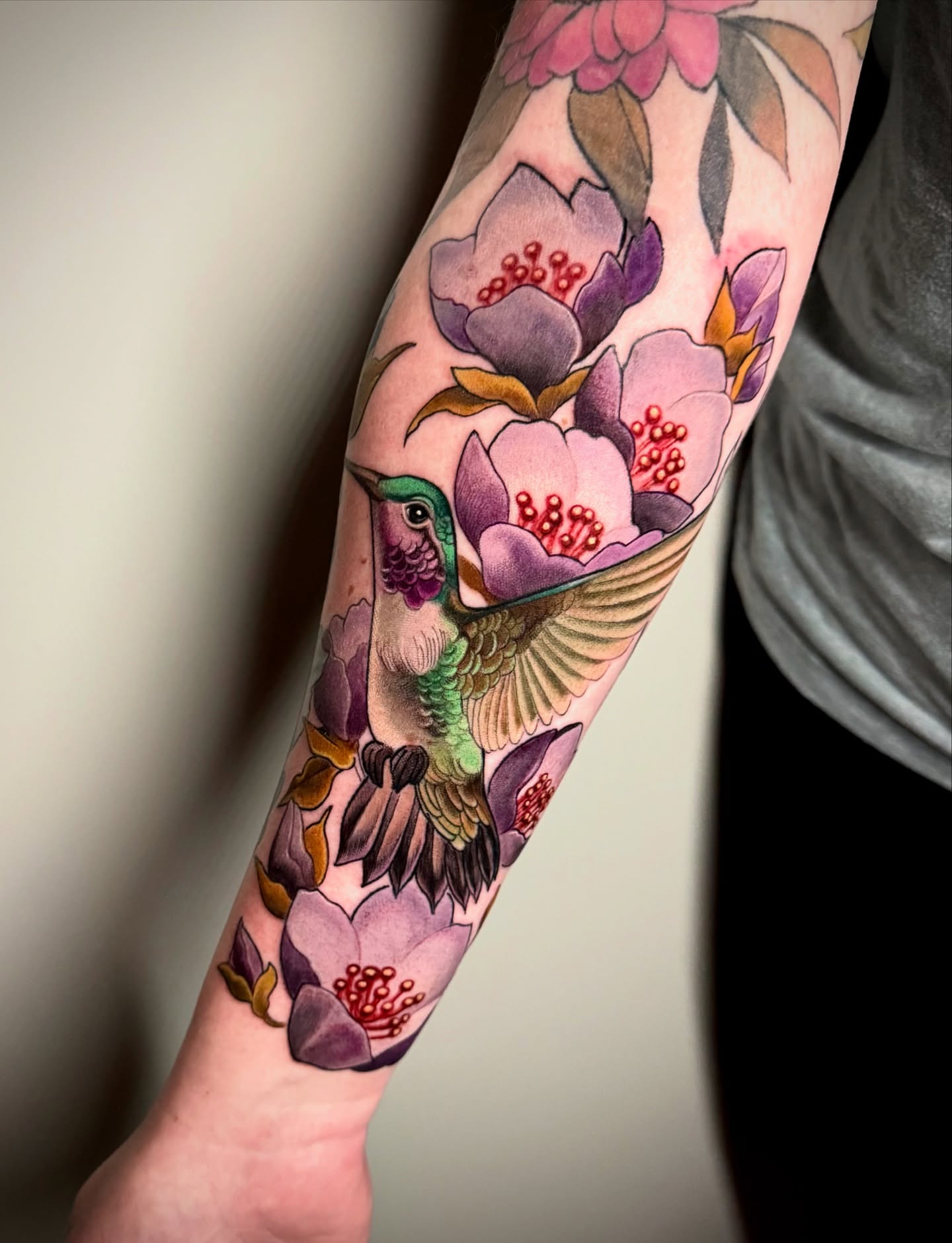 Hummingbird and flowers new school tattoo on the forearm by Jessica Brown