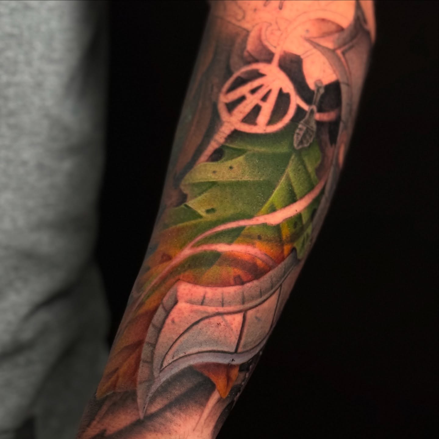 Leaf and anarchy symbol realism tattoo on the forearm by James Hall